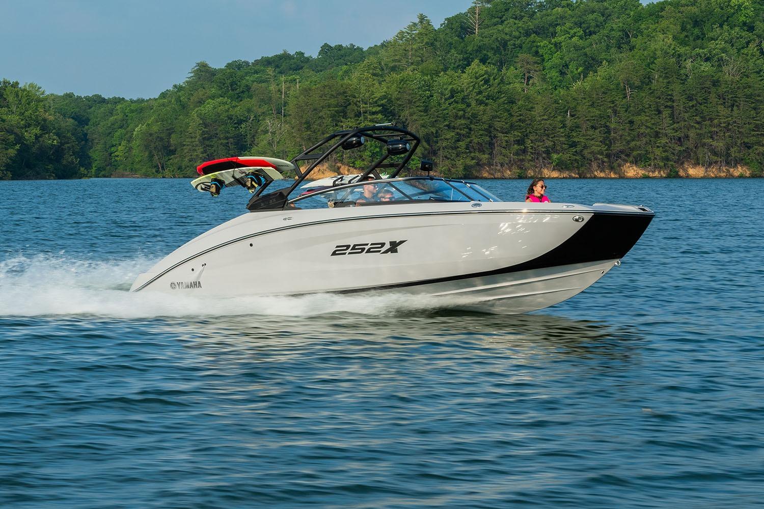 Manufacturer Provided Image: 2026 Yamaha Boats 252XE cruising on a scenic lake with lush green forest backdrop.