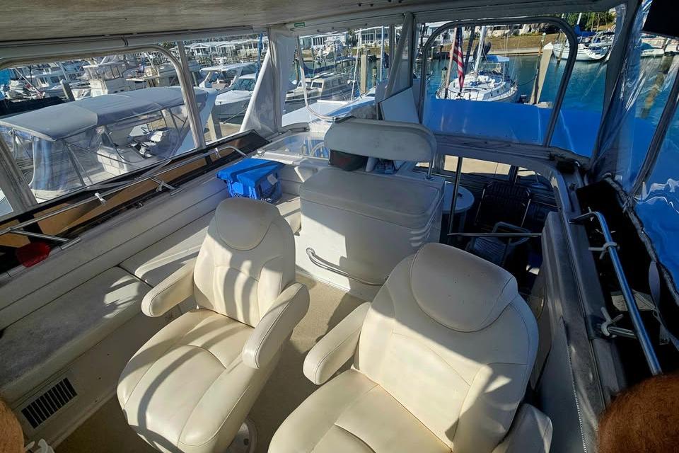 Interior view of 1998 Mainship 47 Motor Yacht with white seating and marina backdrop.
