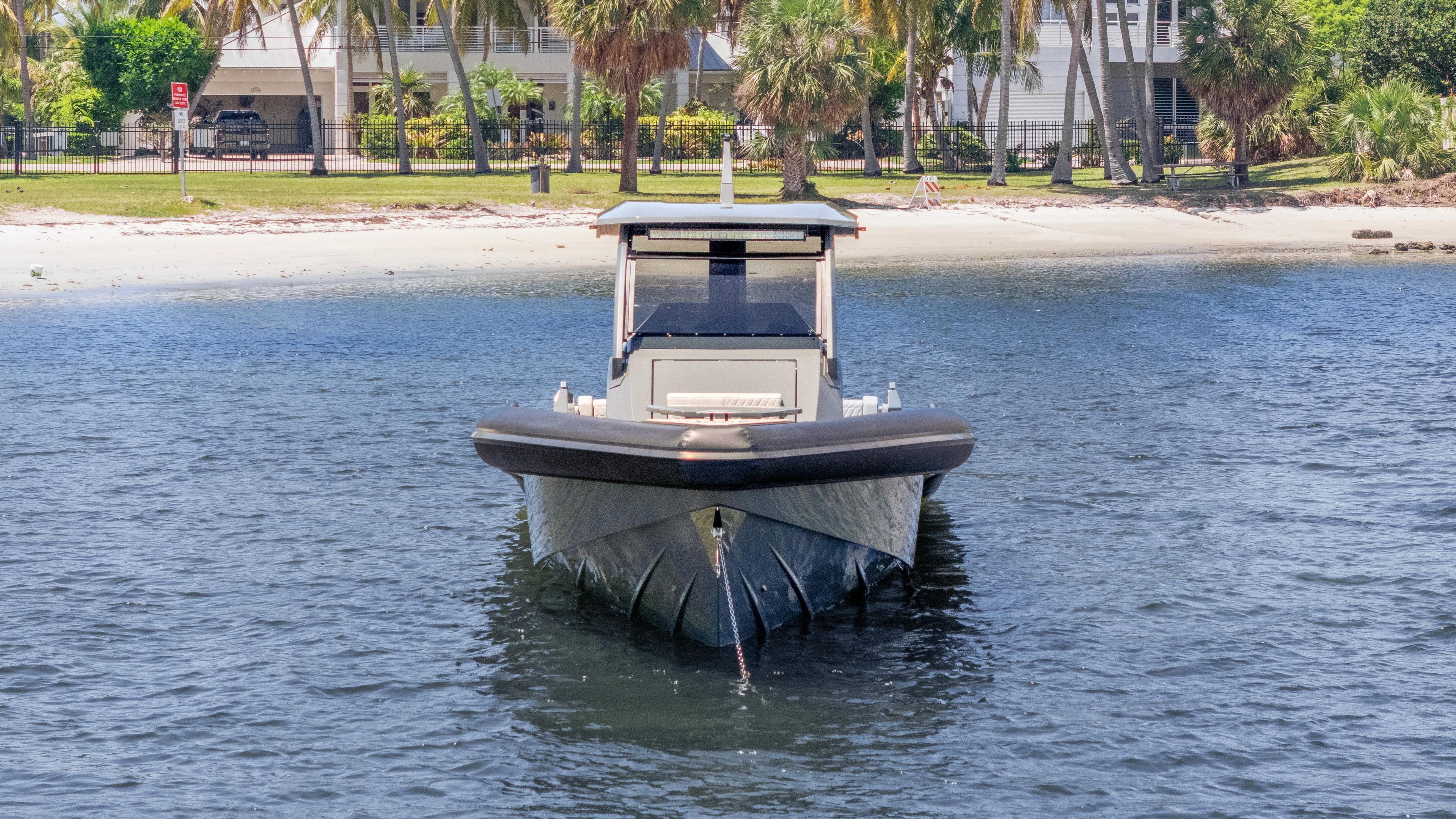 2025 Skipper-BSK 38 boat on water near a sandy beach with palm trees.