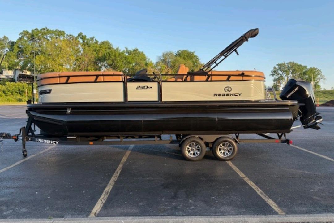 2026 Regency 230 DL pontoon boat on trailer in parking lot, side view.