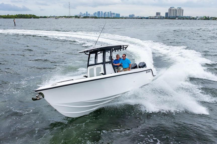 2027 Reef Runner 280 boat cruising on open water with city skyline in background.