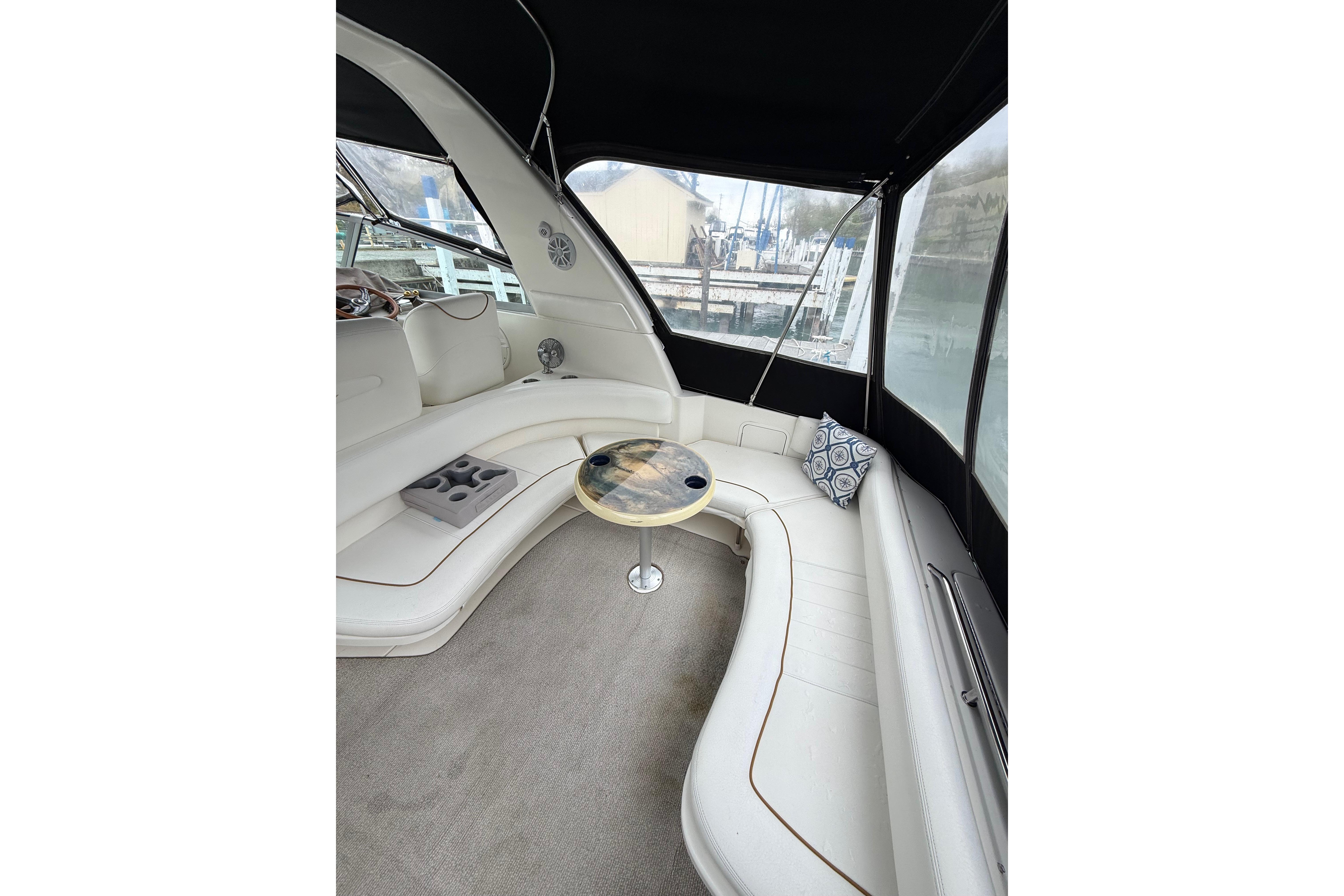 1999 Sea Ray Sundancer 310 interior with white seating, table, and decorative pillows.