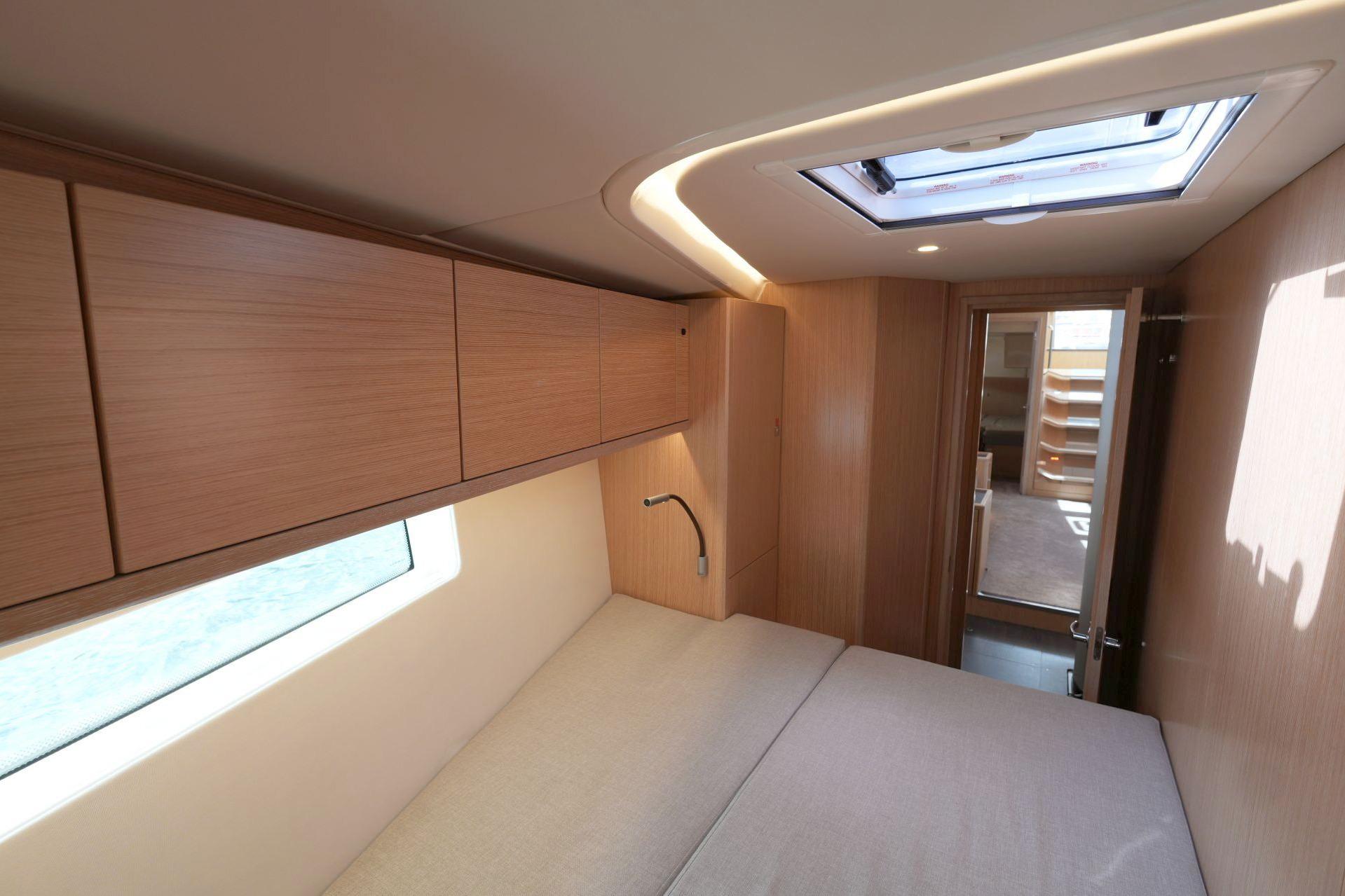 Interior of 2018 Bavaria C57 Style yacht cabin with modern wood finish and skylight.