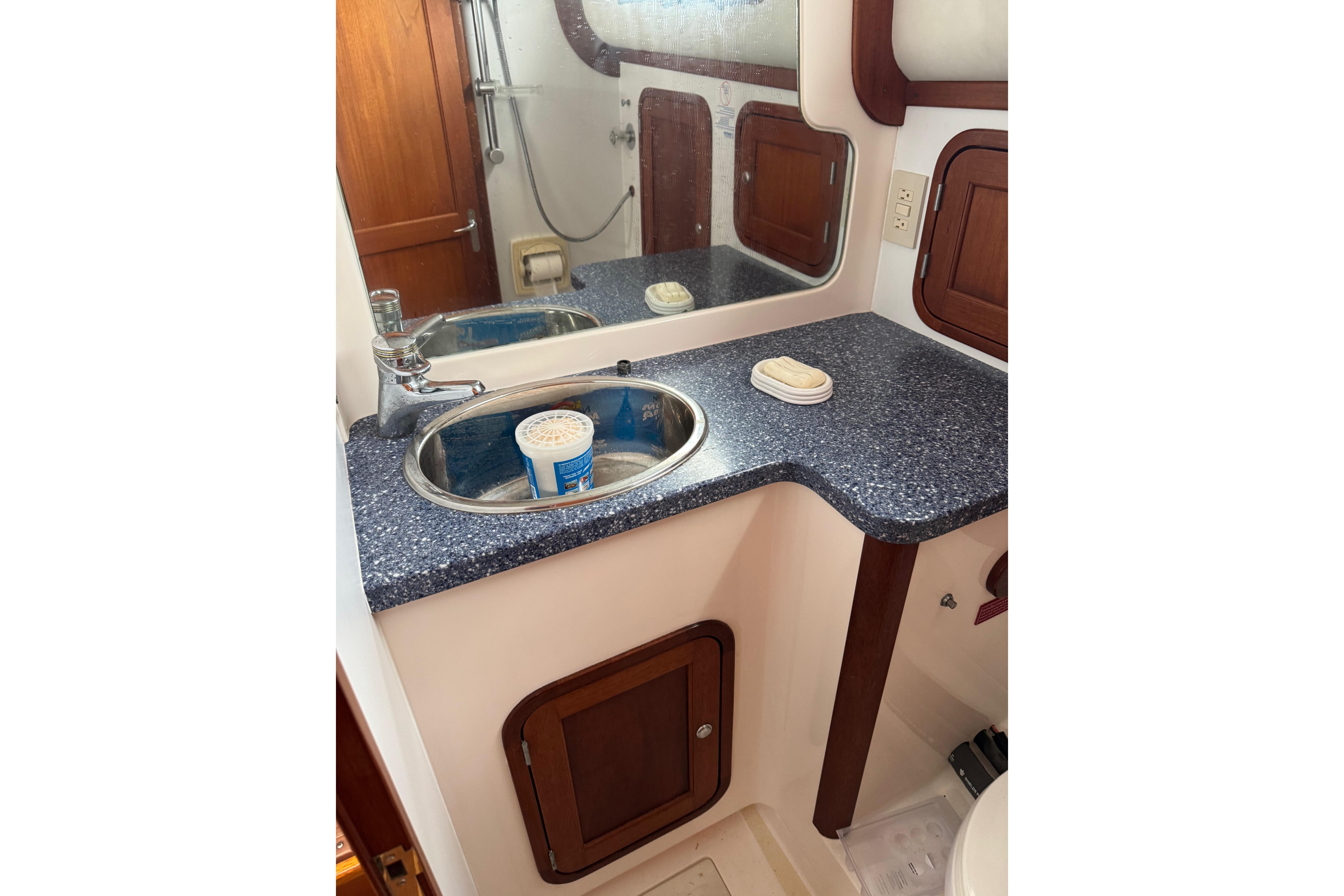 Bathroom sink area in 2001 Legacy Yachts Express, featuring countertop and mirror.