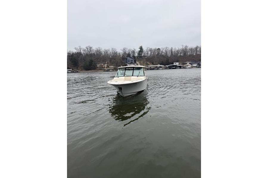 2025 Grady-White Freedom 325 boat on a calm lake with wooded shoreline.