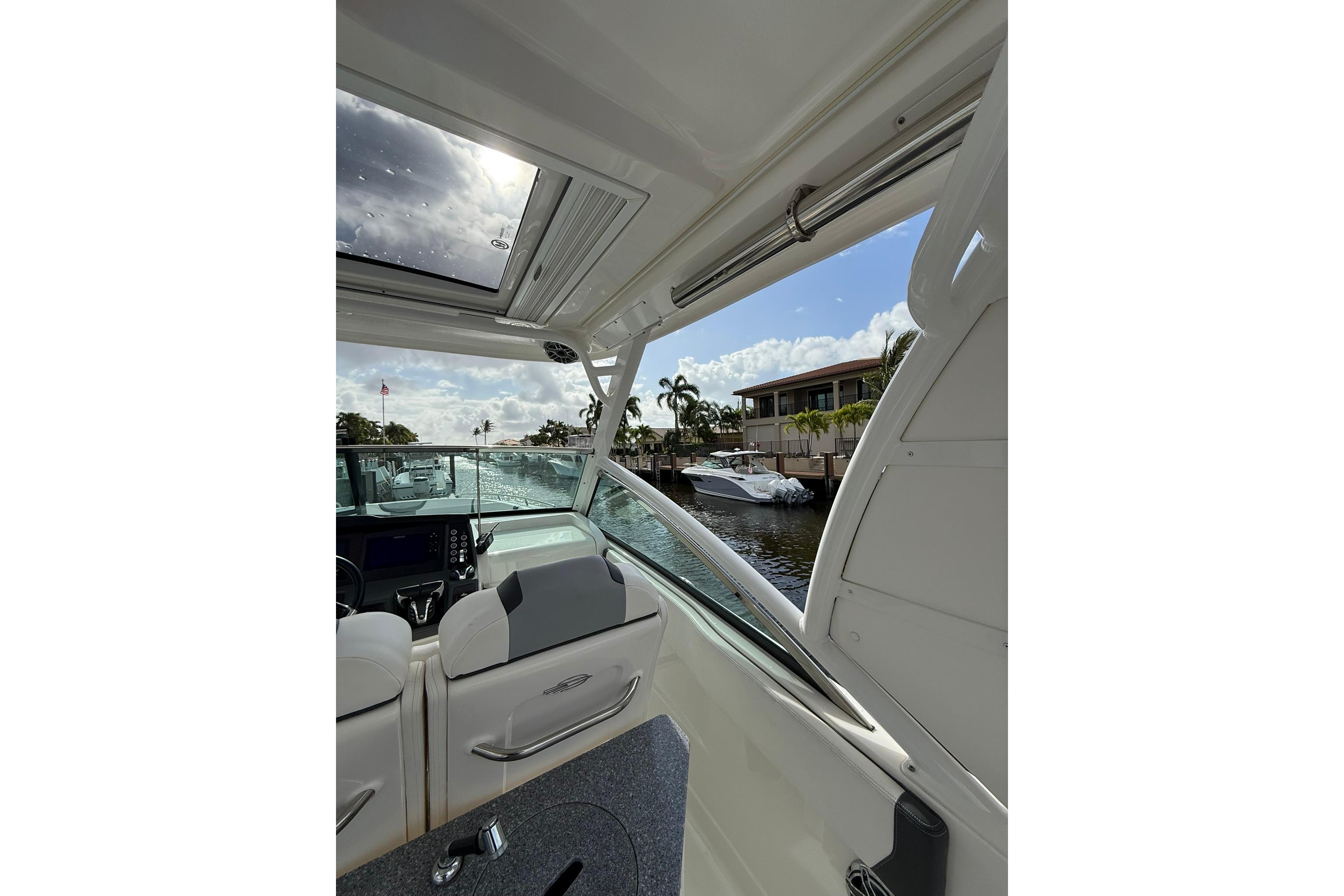 Interior view of 2023 Chaparral 300 OSX boat with open sunroof and waterfront scenery.