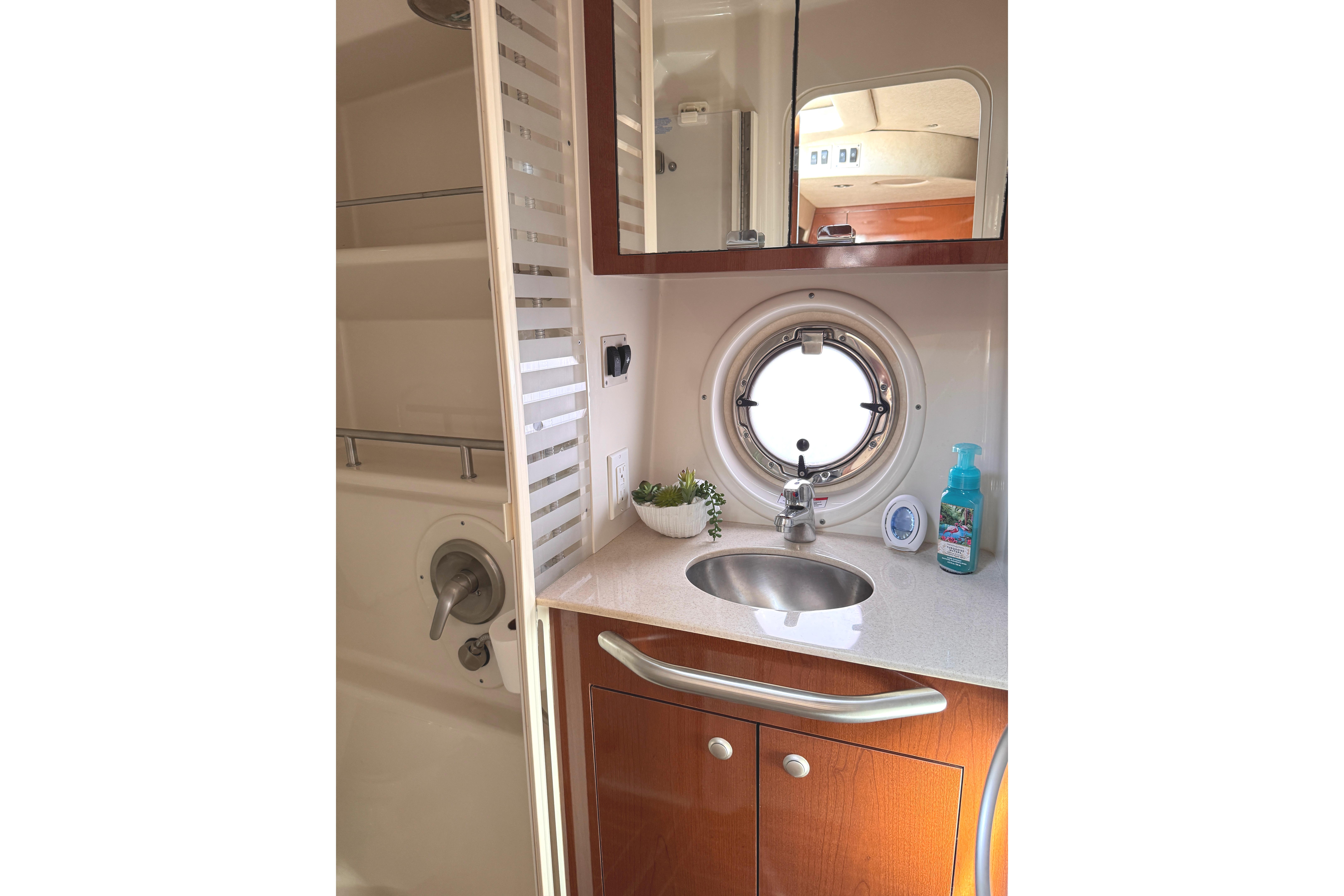 2008 Sea Ray Sundancer 350 bathroom with sink, porthole, and shower area.