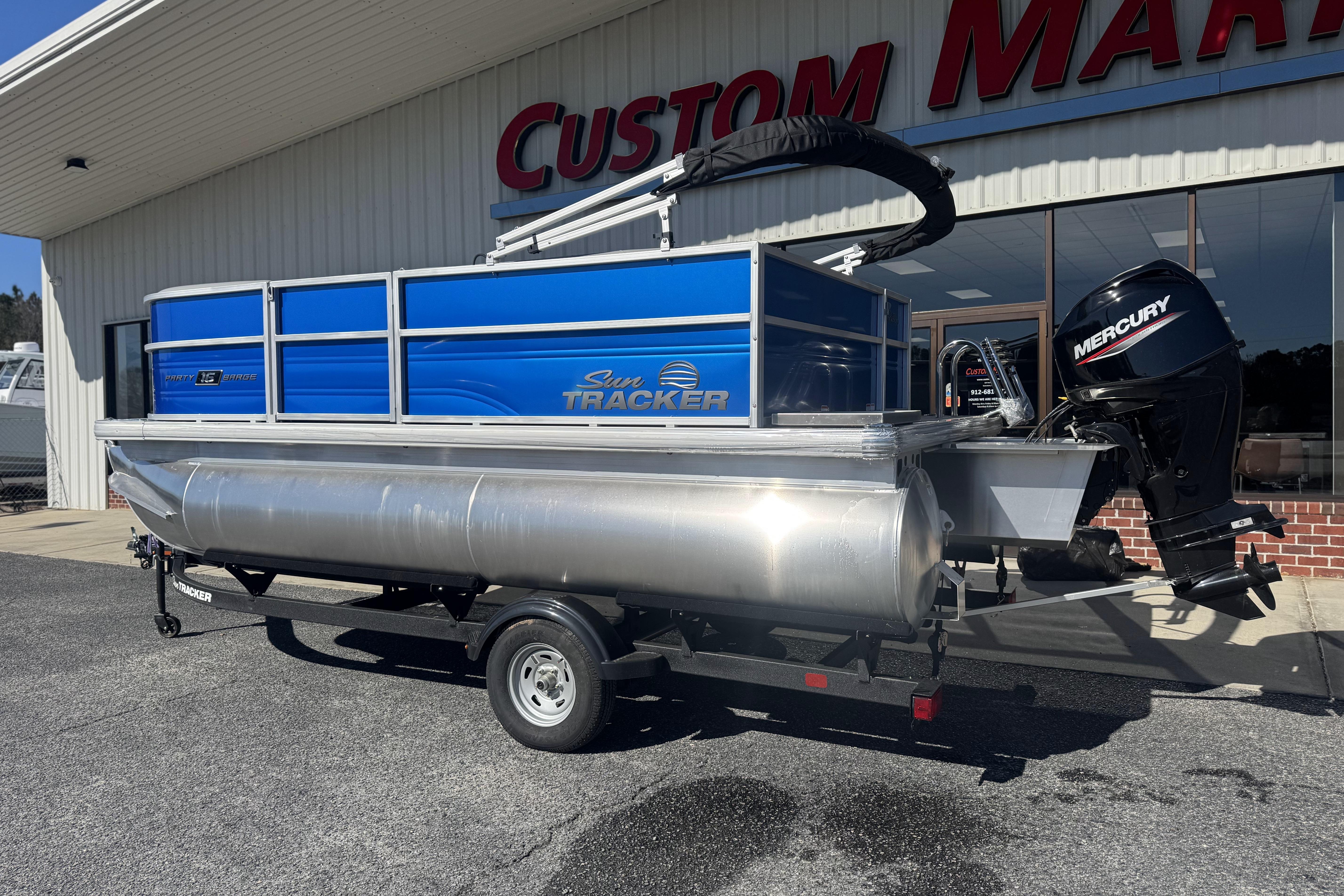 2026 Sun Tracker Party Barge 16 DLX pontoon boat with Mercury engine, parked outside dealership.