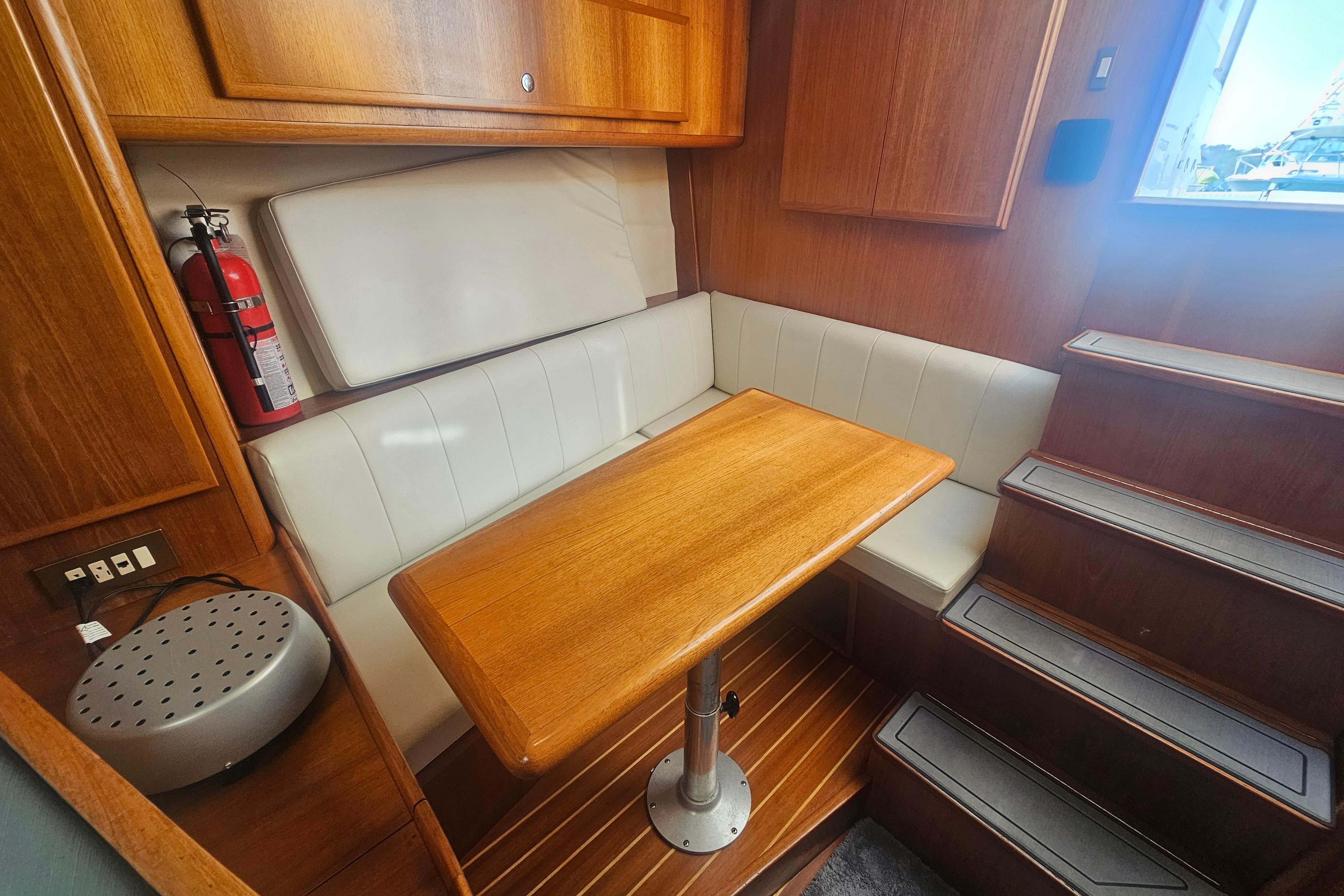 2003 Topaz 32 Express cabin interior with wooden table, white seating, and stairs.