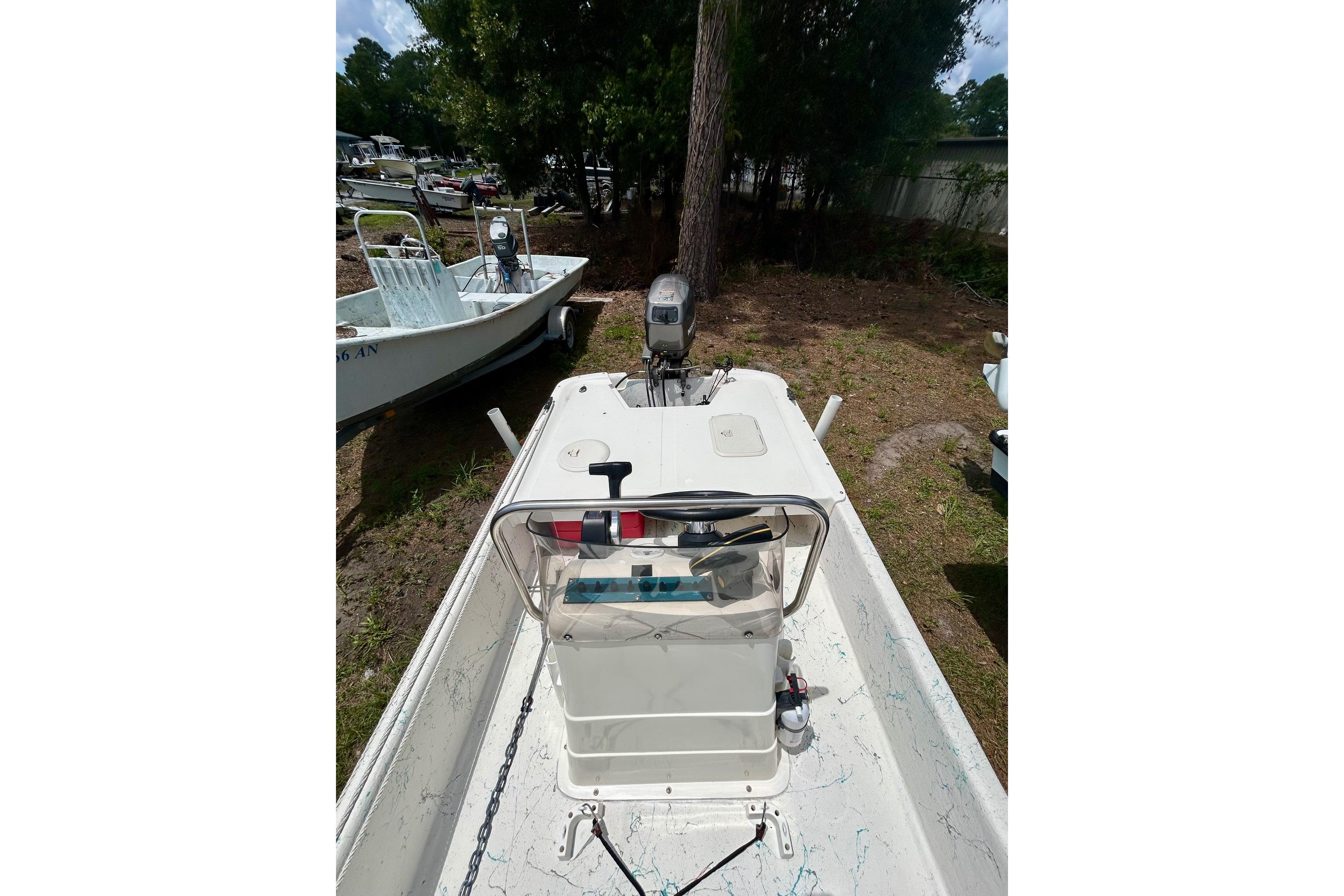 2002 Sundance K16CC boat with outboard motor, parked on grassy area near trees.