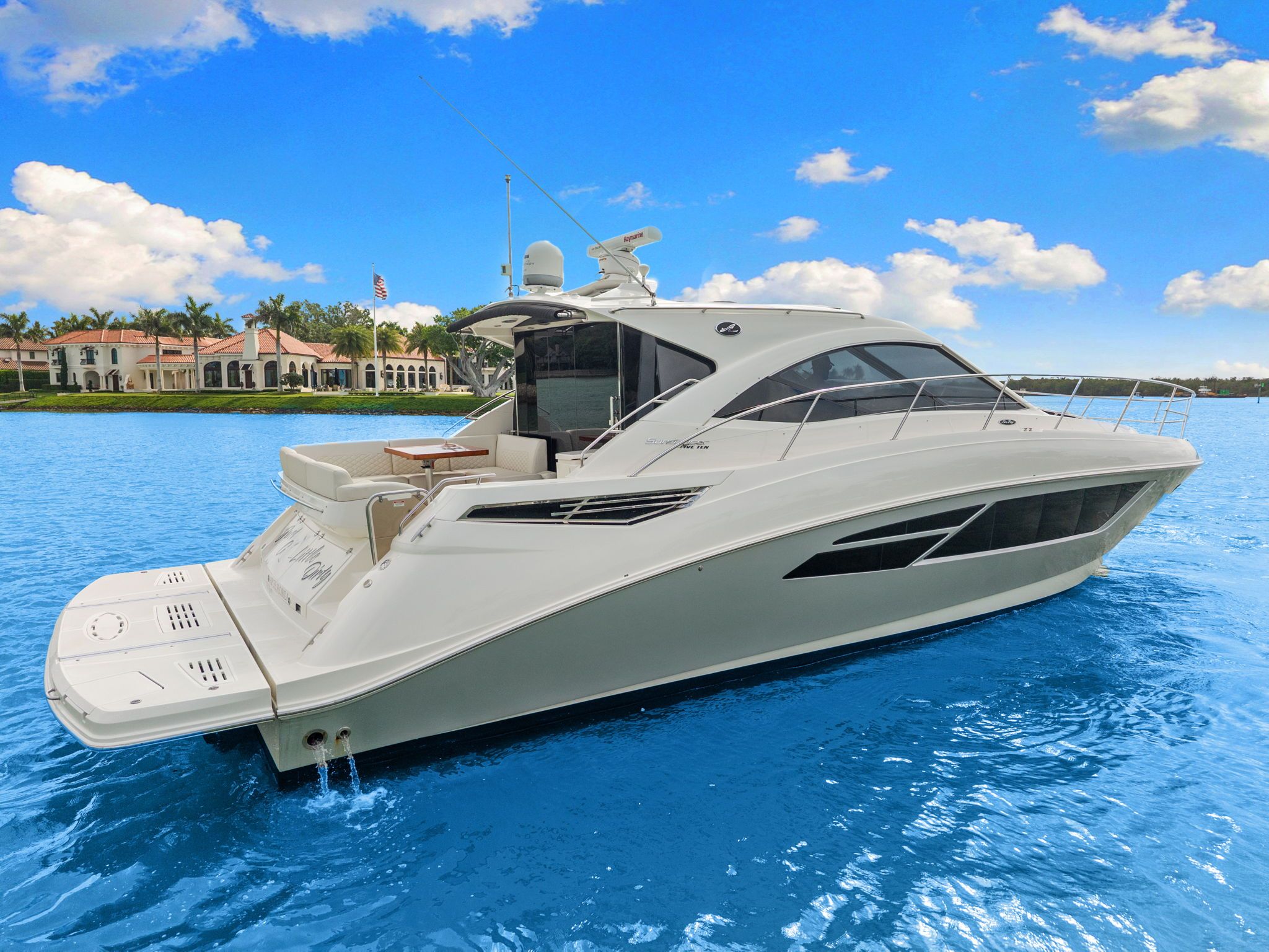The 2017 Sea Ray Sundancer 510 is on calm blue water near a coastline with villas.