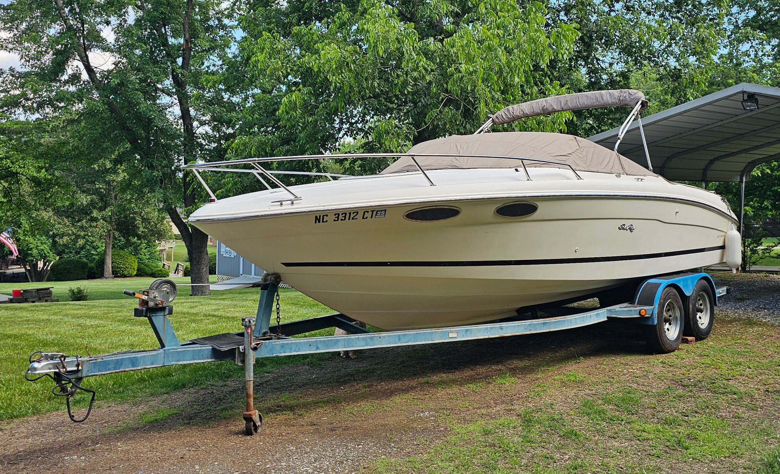 A 1997 Sea Ray 230 Overnighter Signature on a trailer in a grassy area.