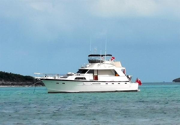 A white yacht is anchored in turquoise water, surrounded by islands.