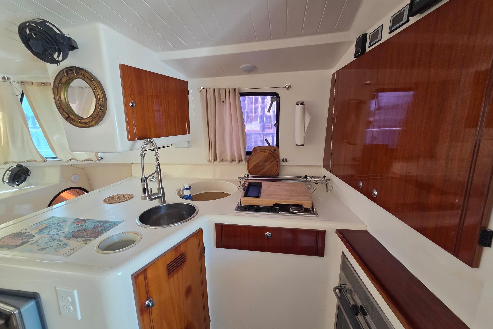 Interior of 2000 Fountaine Pajot Maryland 37 yacht kitchen with wood cabinets and porthole.