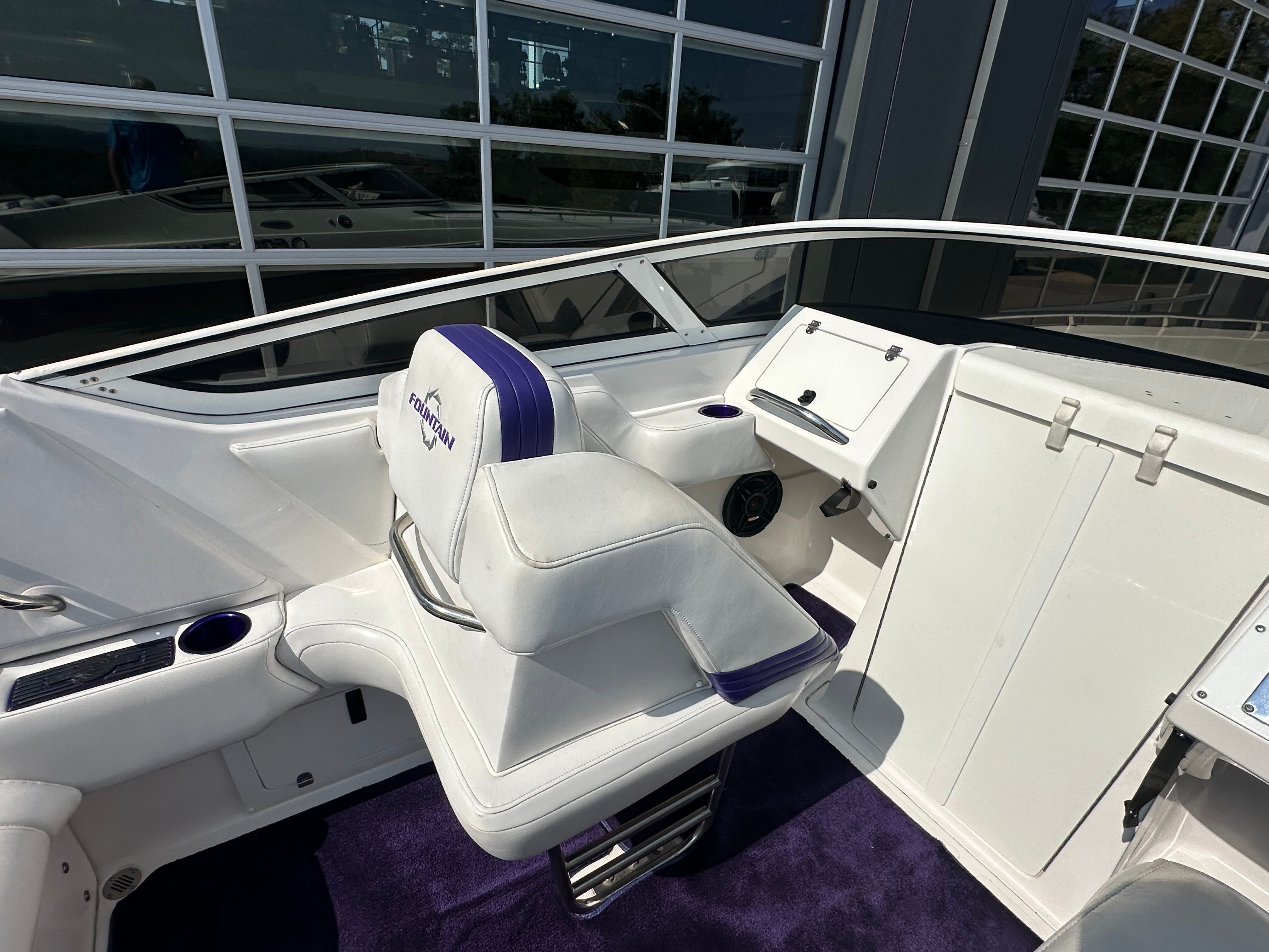The image shows the cockpit of a 2006 Fountain 29 Fever boat with white and purple seats.