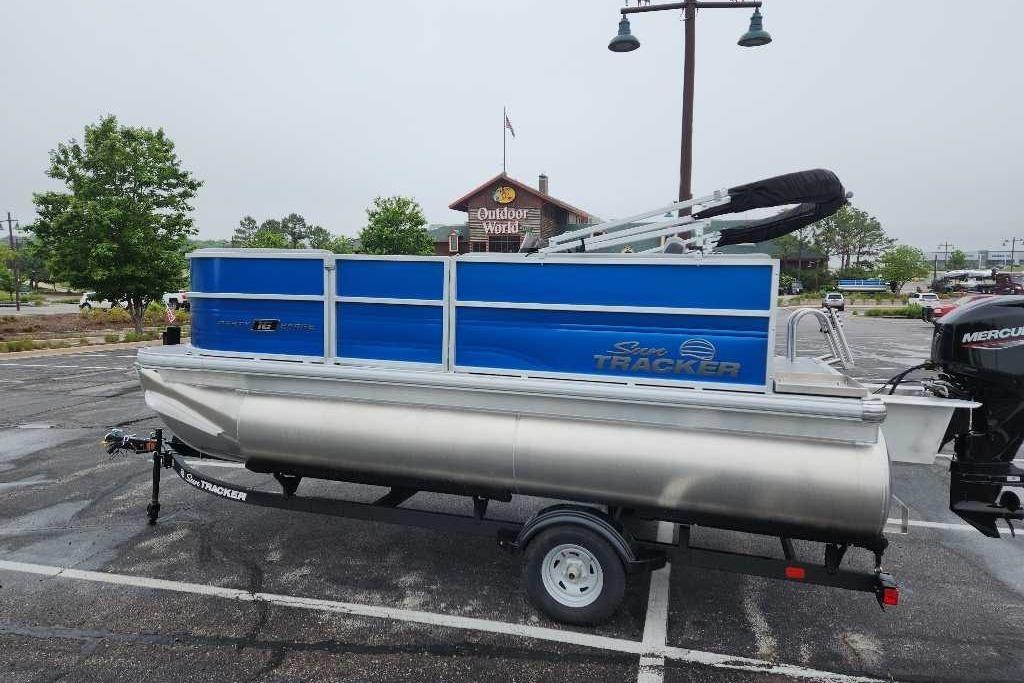 2026 Sun Tracker Party Barge 16 DLX pontoon boat on trailer in parking lot.