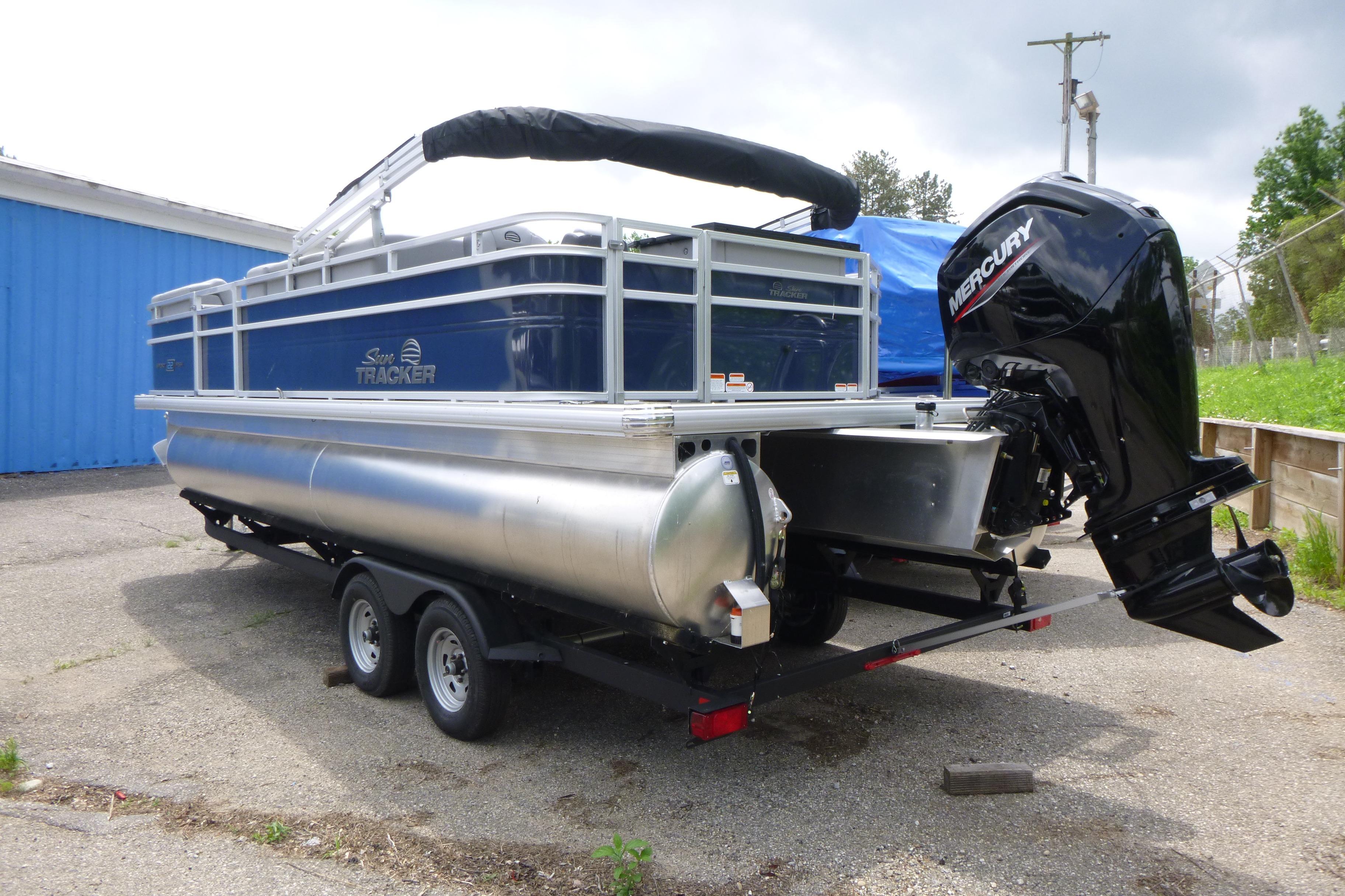 2026 Sun Tracker SportFish 22 DLX pontoon boat with Mercury outboard motor on trailer.