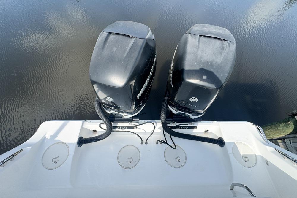 Twin outboard motors on a 2018 Mako 284 Center Console boat, docked on calm water.