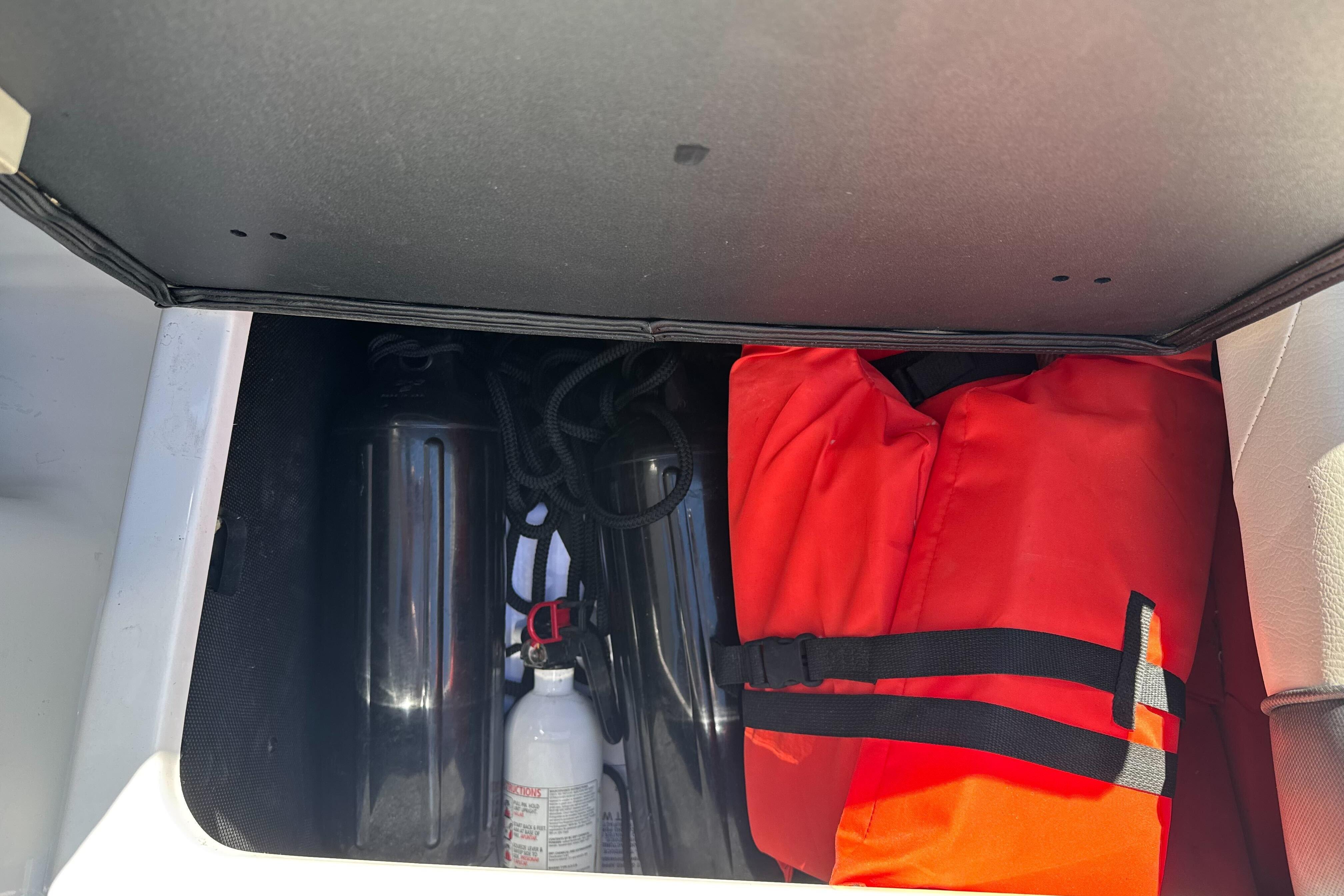 Storage compartment in a 2015 Axis A20 boat with life jacket and fire extinguisher.