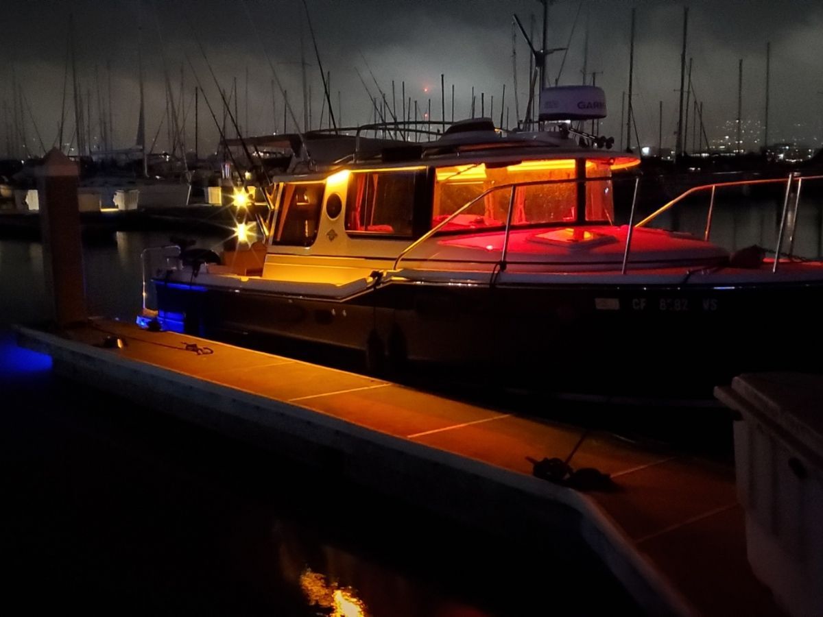 A 2020 Ranger Tugs R-23 boat is illuminated at a dock during nighttime.