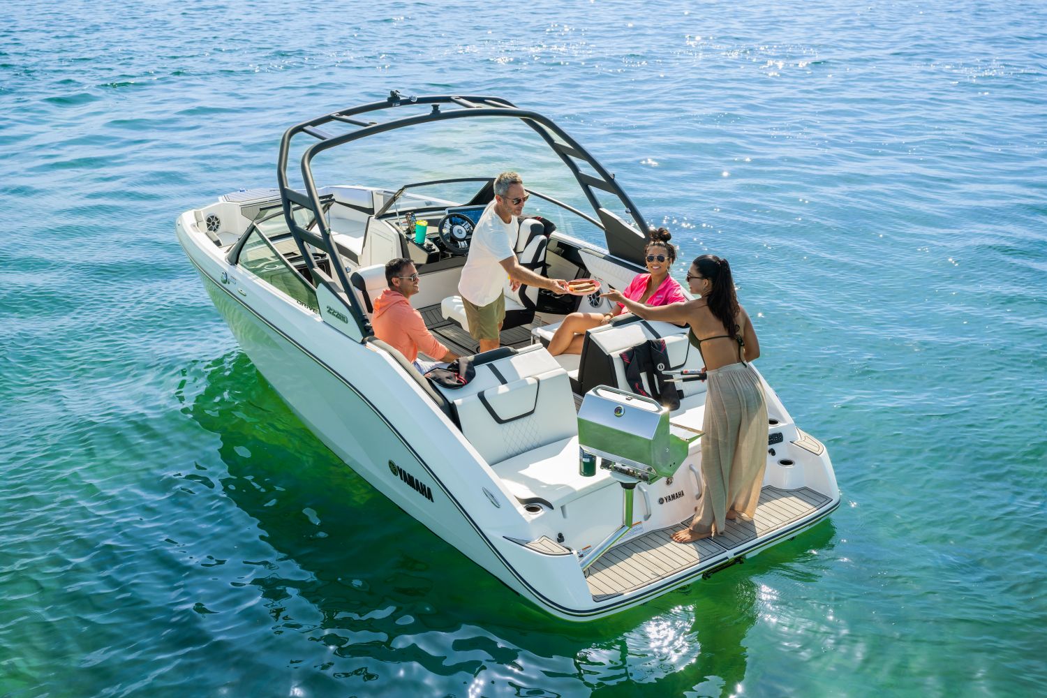 Four people enjoy a boat ride on a Yamaha 222SD on calm waters.