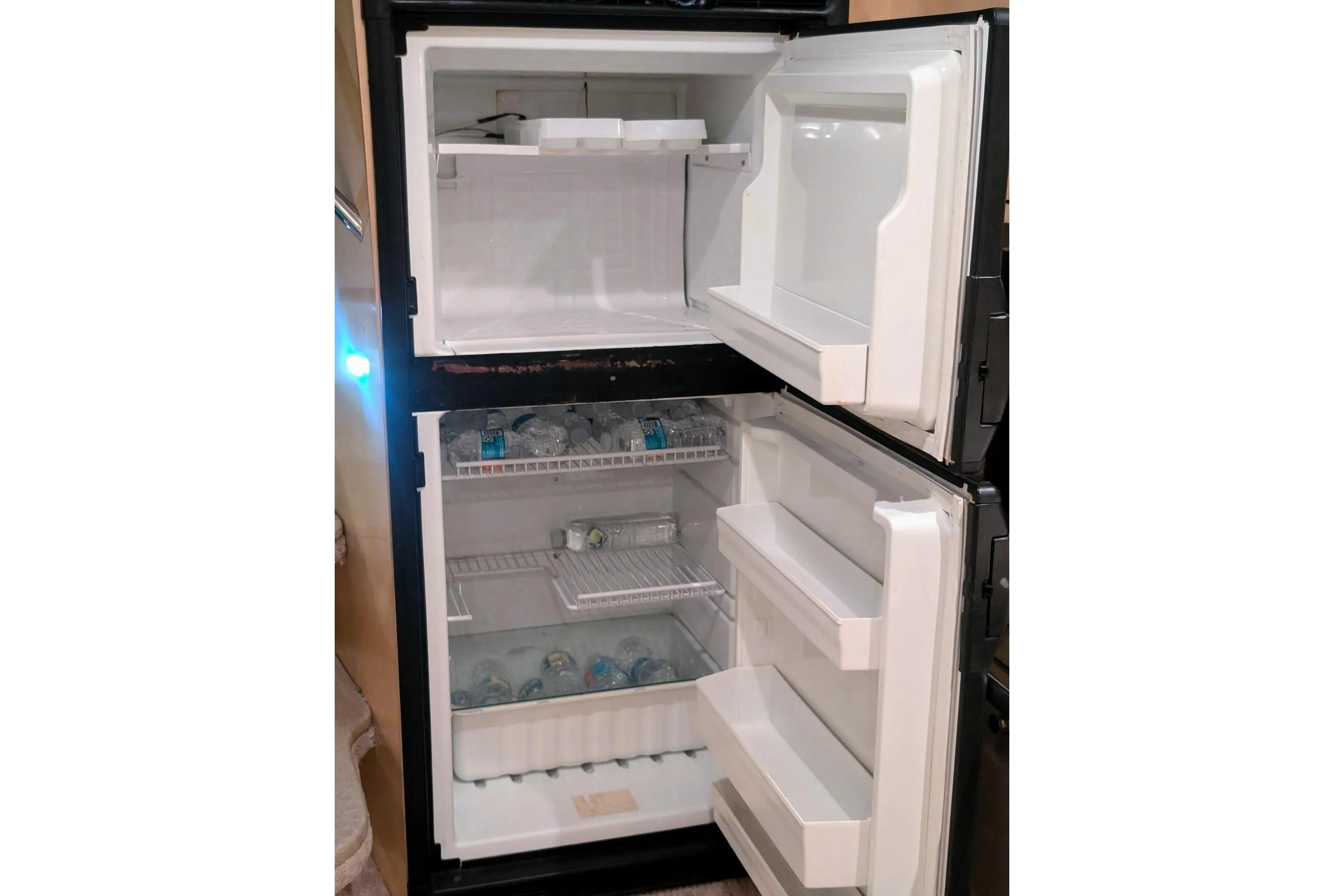 Open refrigerator on a 2000 Sea Ray 380 Sundancer, stocked with bottled water.