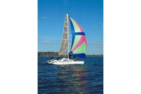 Sailboat Corsair F24 MKI 1994 with colorful spinnaker on open water.