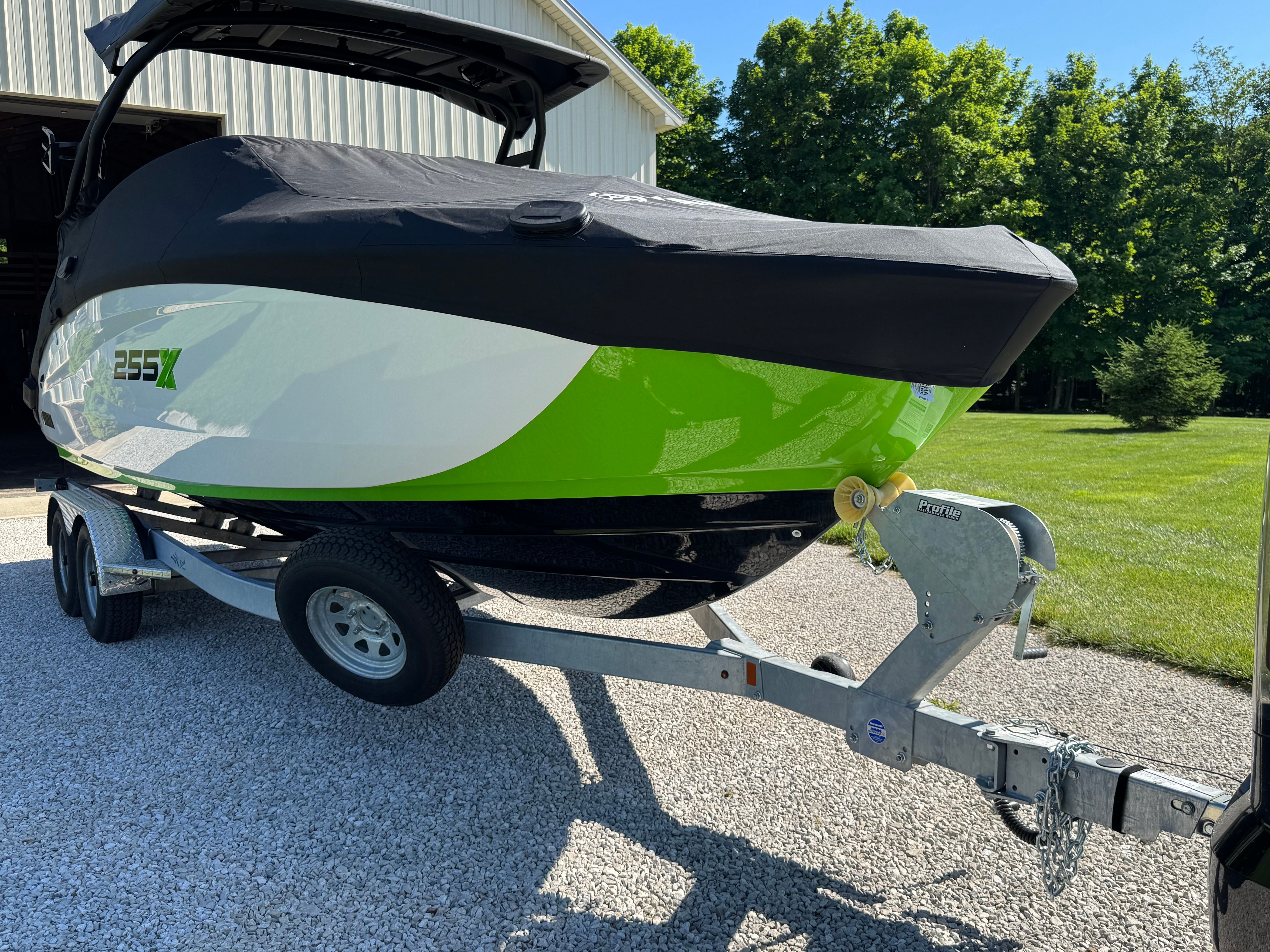 2022 Yamaha 255XD boat on a trailer, featuring a green and white hull, covered.