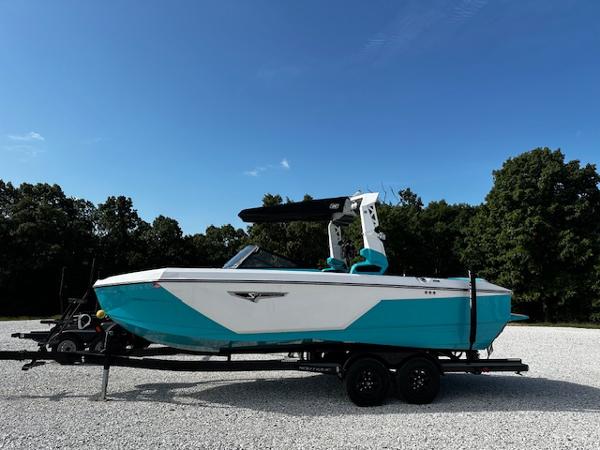 2022 Nautique S23 boat on trailer, turquoise and white, parked outdoors.