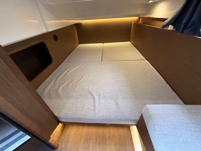 Interior of a 2021 Jeanneau NC 1095 with a cozy sleeping area and wood paneling.