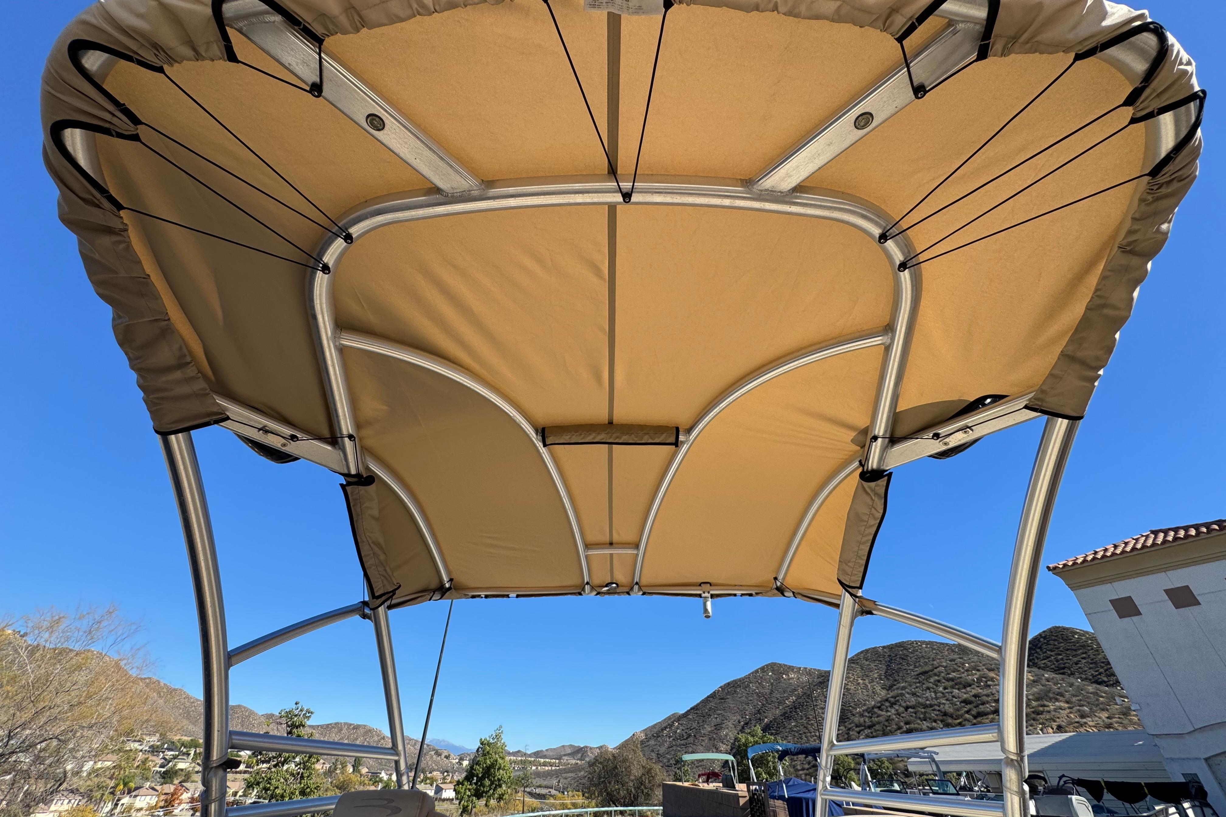 Bimini top of 2013 Bennington 2575QCW I/O boat against clear blue sky.