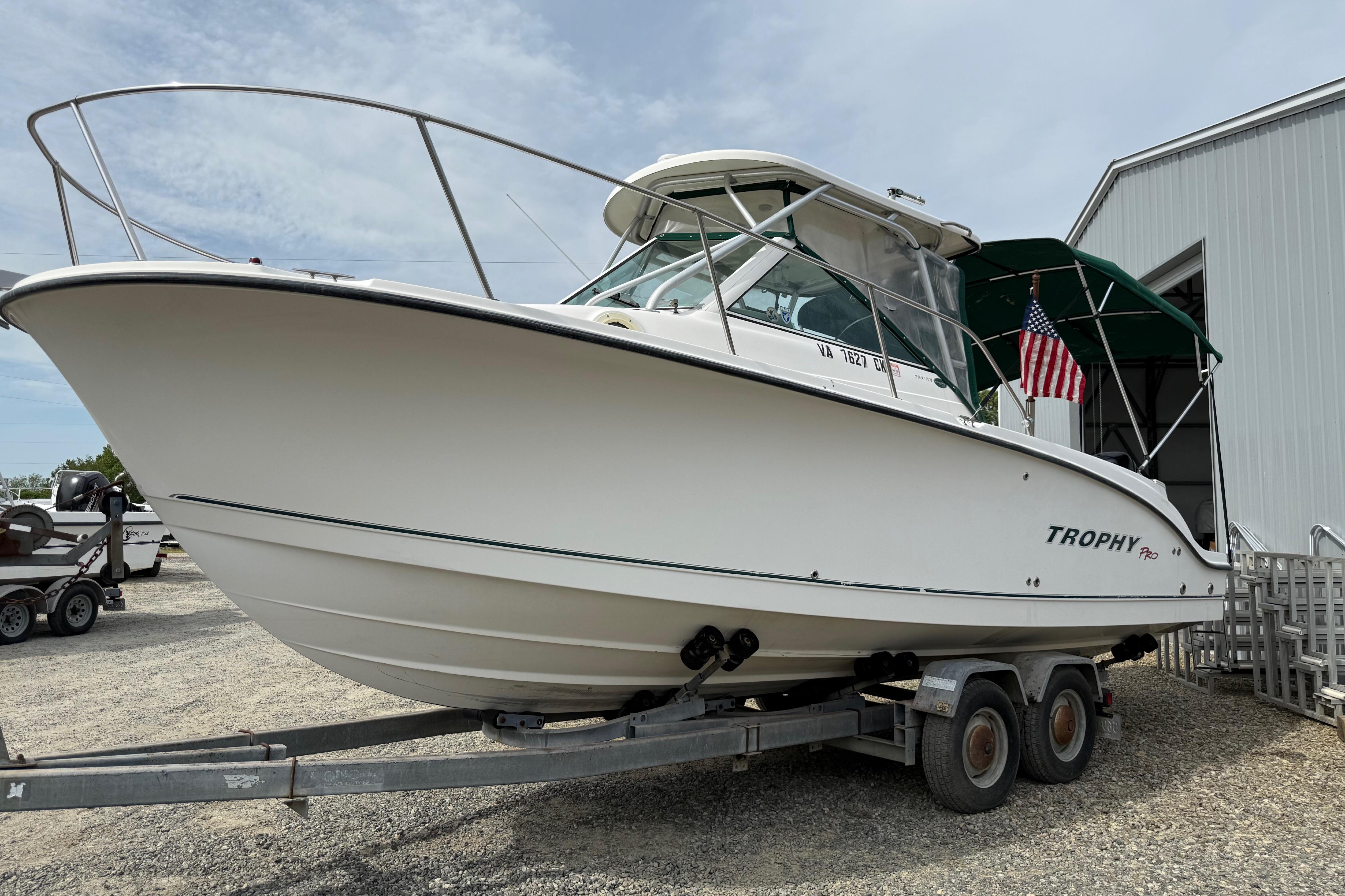 2006 Trophy 2502 Walkaround boat on trailer, parked near a building.