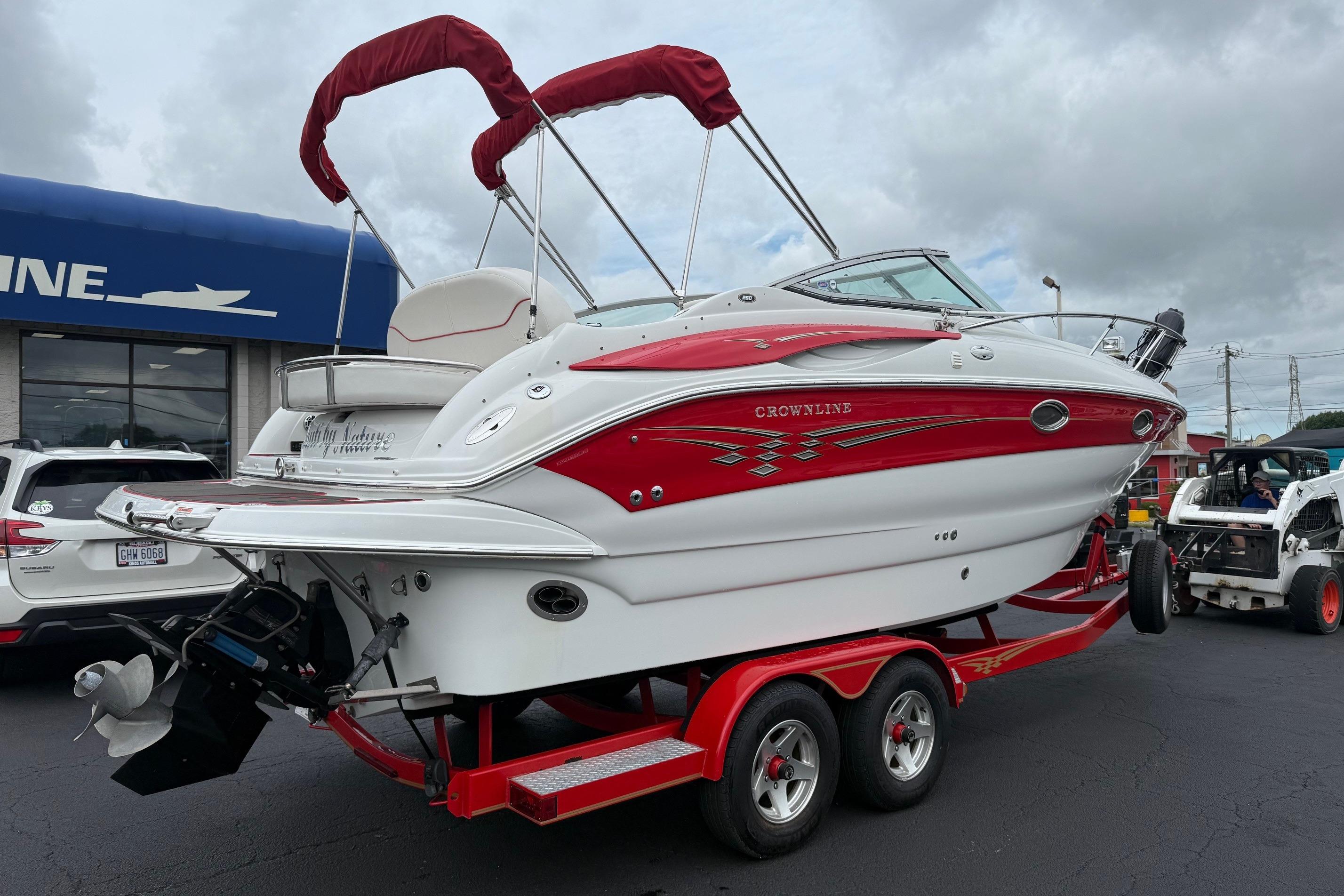 2005 Crownline 250 CR boat on trailer, red and white design, parked outdoors.