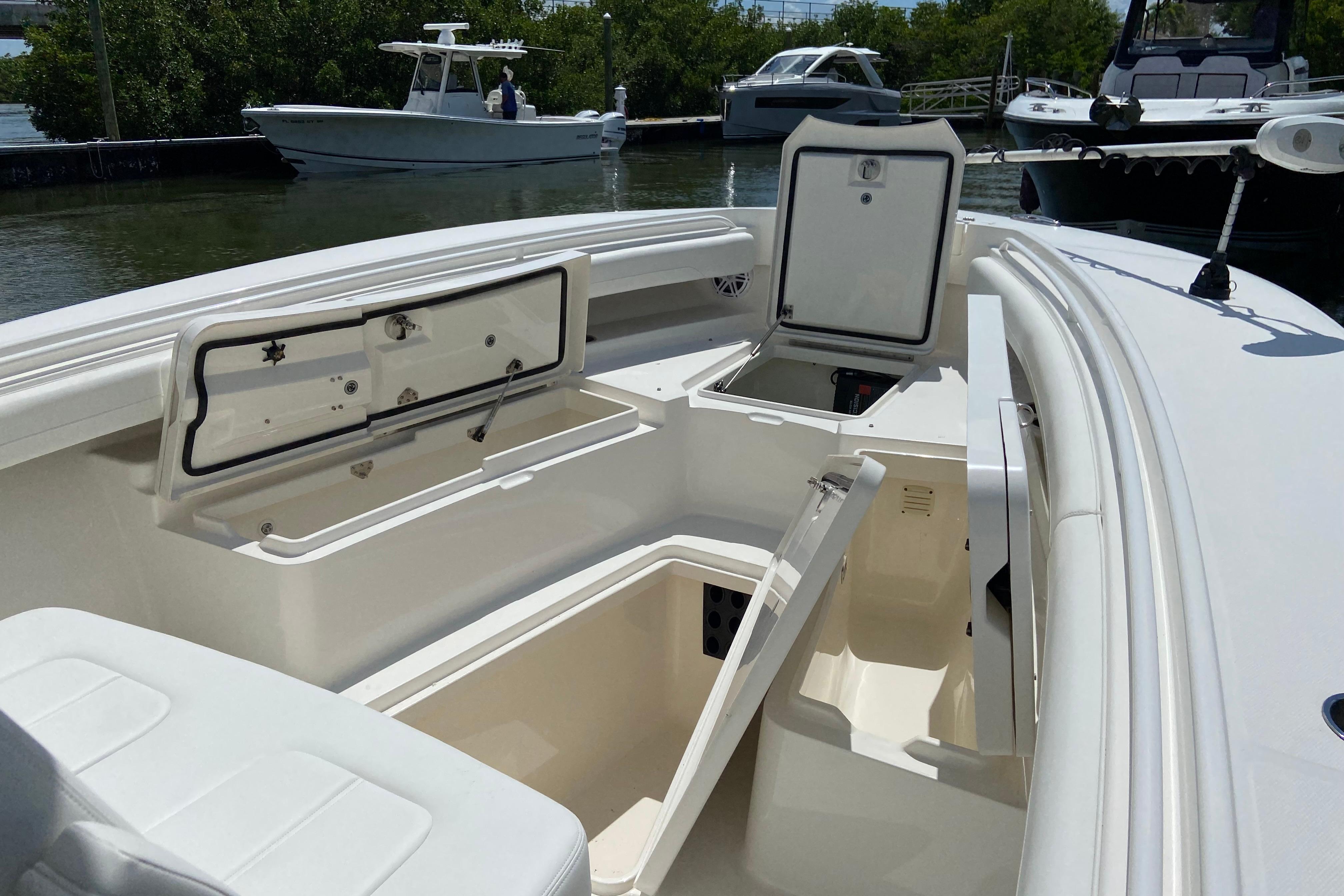 2021 Regulator 28 boat with open storage compartments, docked near other boats.