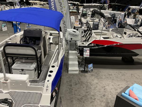 2025 Starcraft SVX 211 OB CC boat with blue canopy at indoor exhibition.