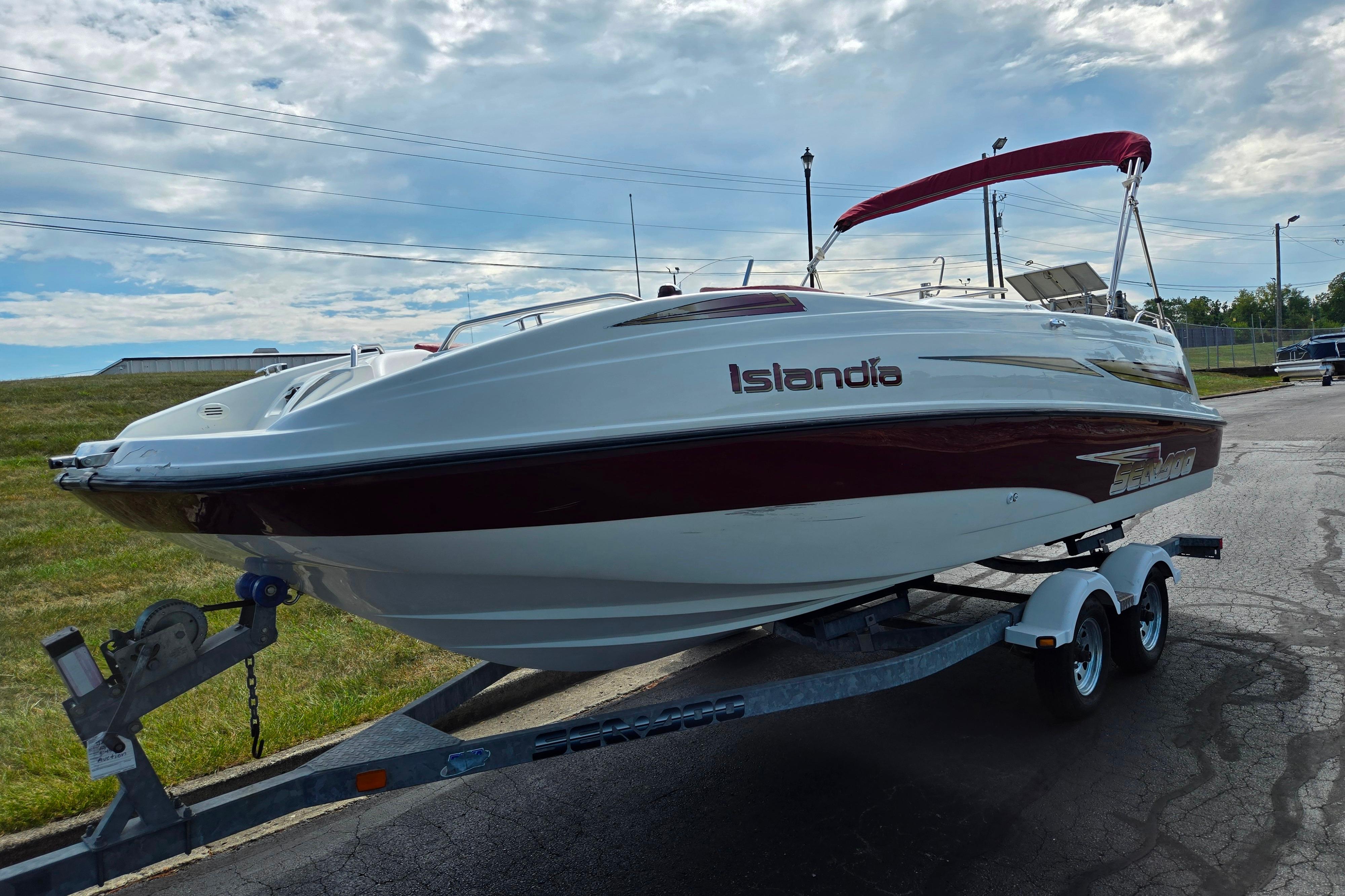2004 Sea-Doo Islandia sport boat on trailer, parked outdoors under cloudy sky.