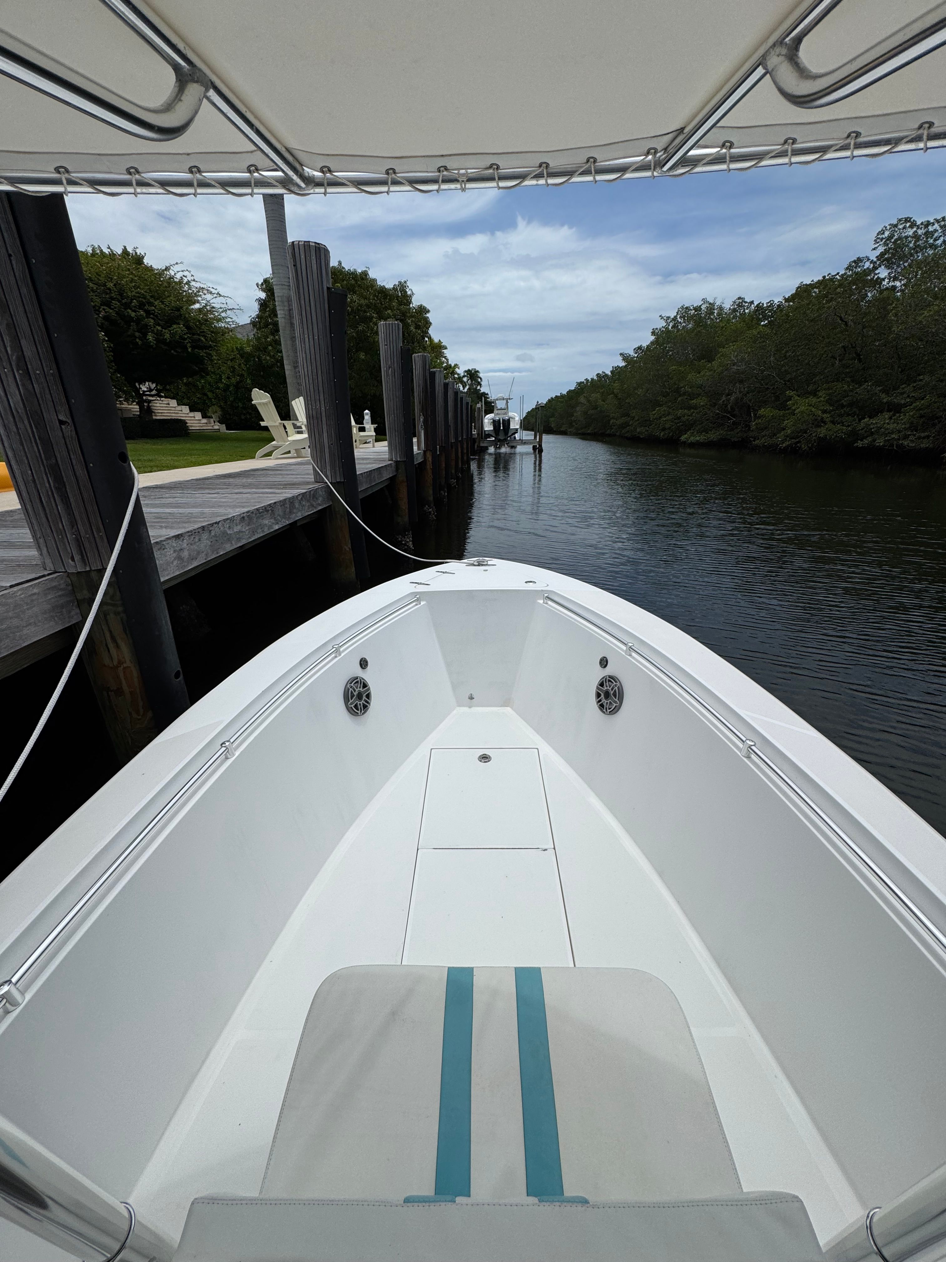 A 2004 Contender 21 boat docked along a calm canal with lush greenery.