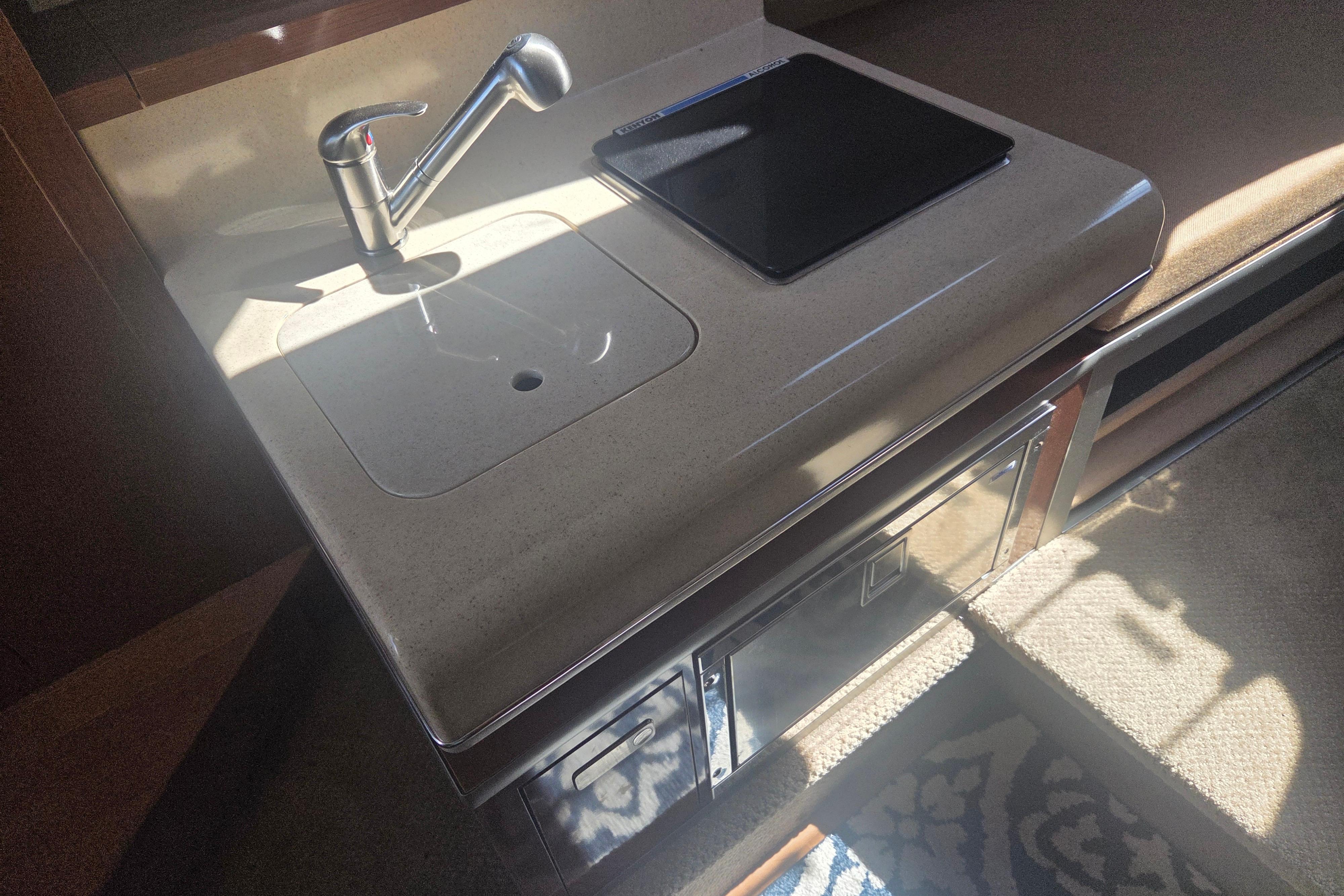 Interior of 2012 Sea Ray Sundancer 260 showing a compact kitchenette with sink and stove.