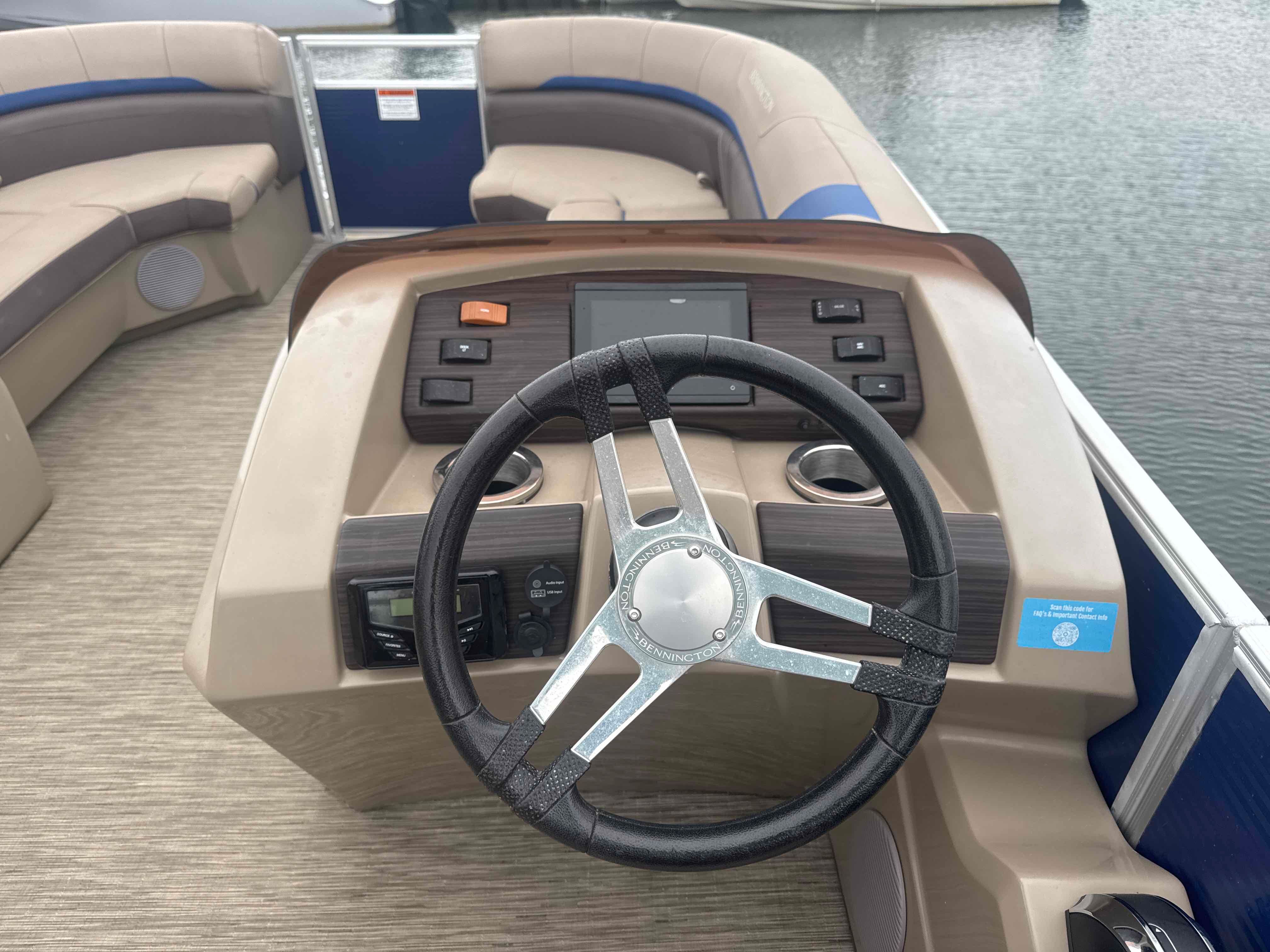 The image shows the helm of a 2023 Bennington 23SXSRC boat with a modern steering wheel.