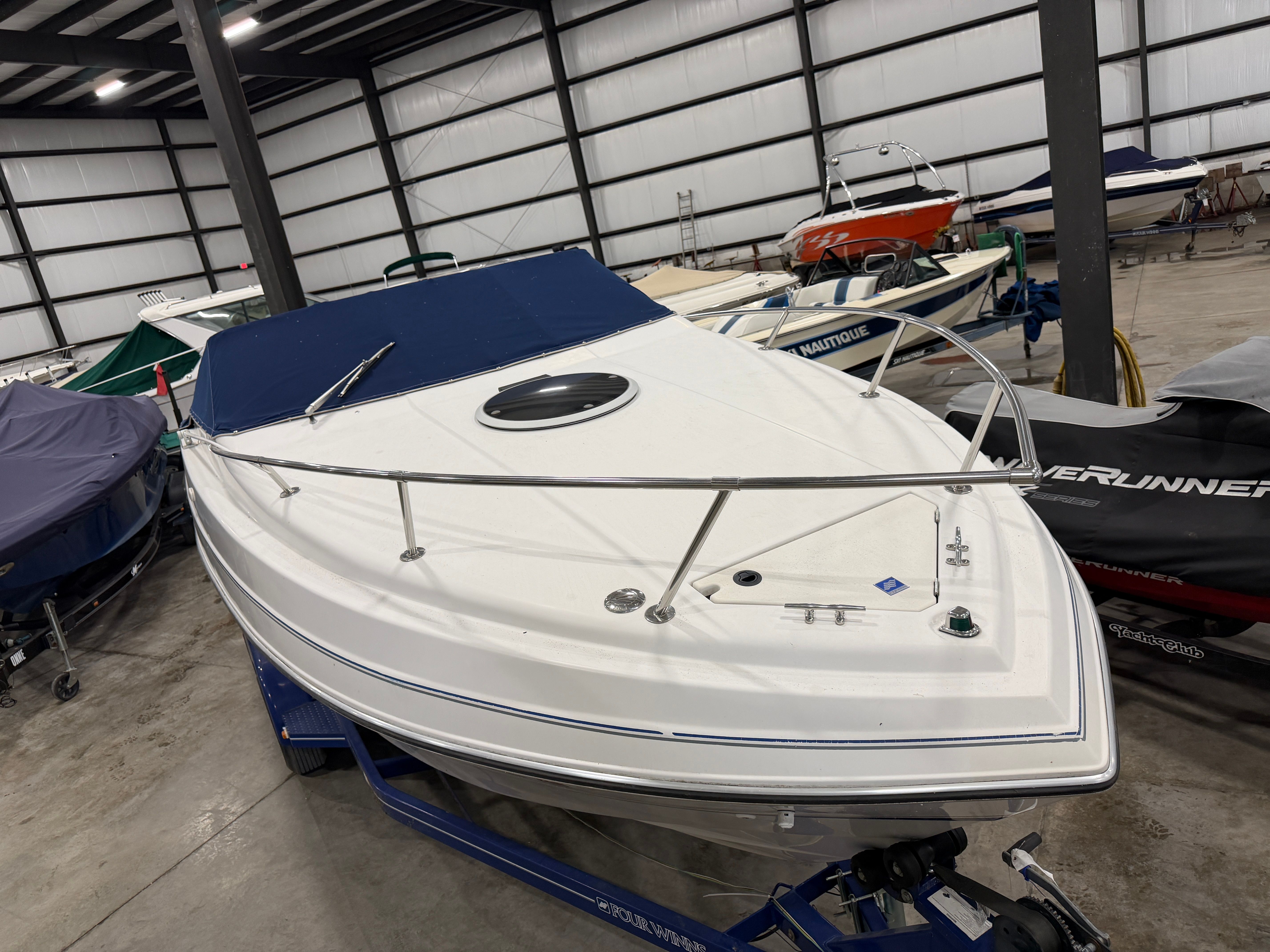 A 1992 Four Winns 225 Sundowner in a storage facility, placed on a trailer.