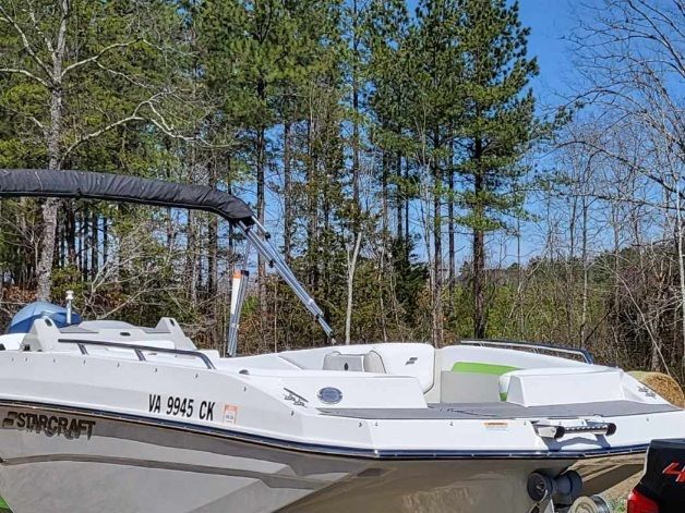 A 2023 Starcraft SVX 191 OB boat on a trailer, surrounded by trees.