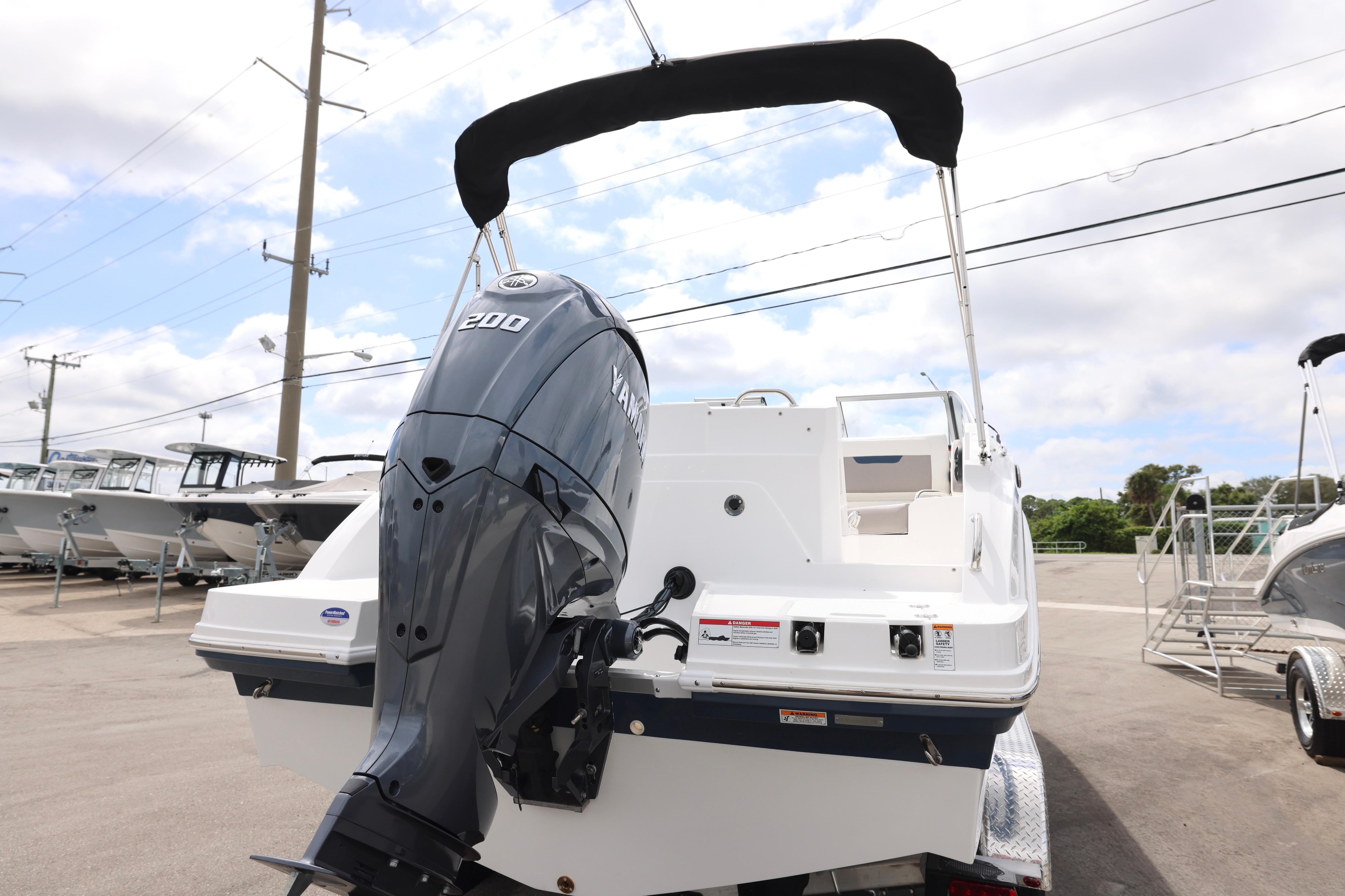 2026 Hurricane SunDeck 235 OB boat with Yamaha 200 engine, parked outdoors.
