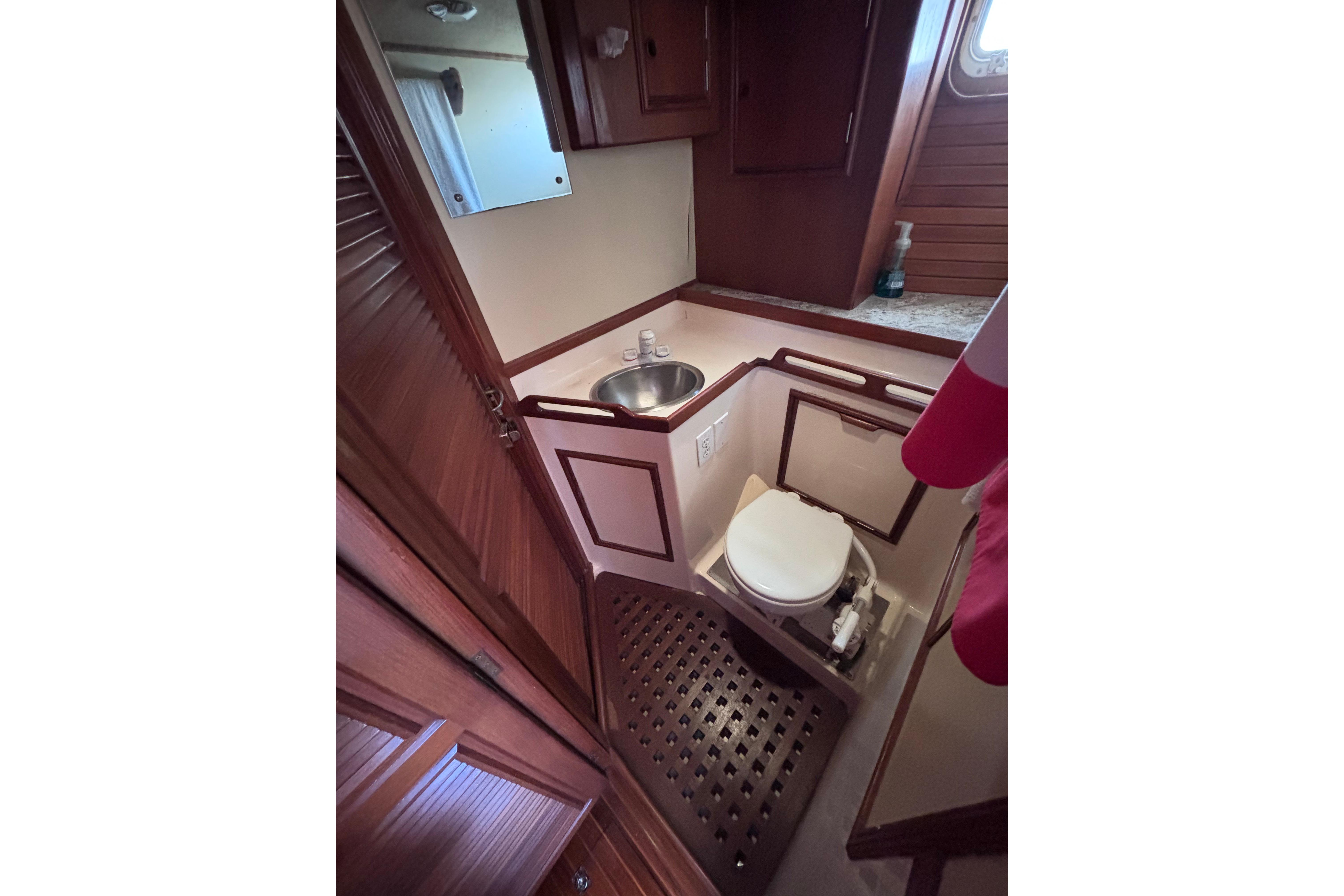 1978 Swift 33 yacht bathroom with wooden cabinetry, sink, and toilet.