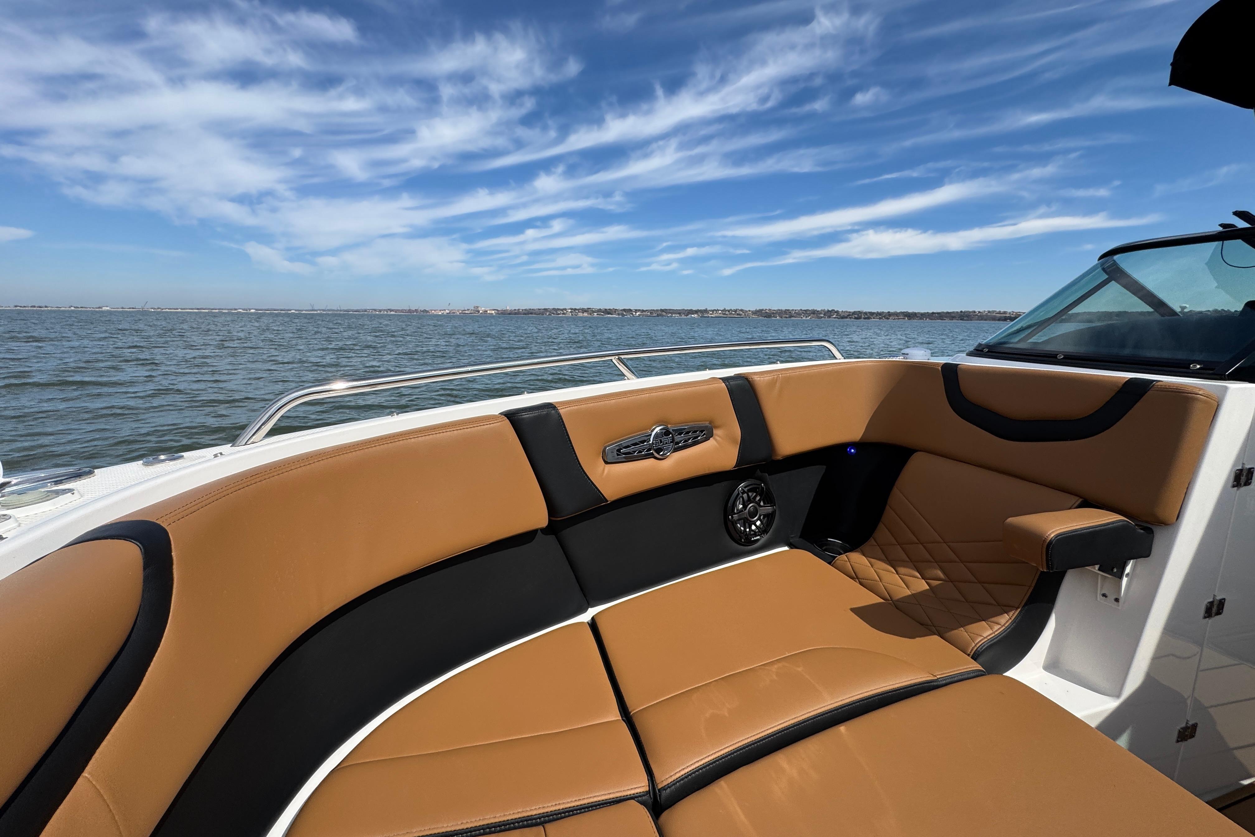 2023 Chaparral 26 Surf boat interior with tan seating, on a sunny day at sea.