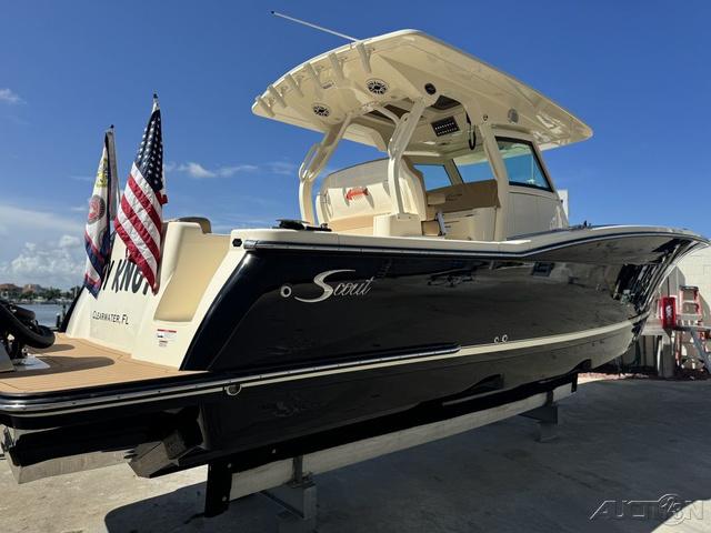 2022 Scout 330 LXF boat with flags, docked under clear blue sky.