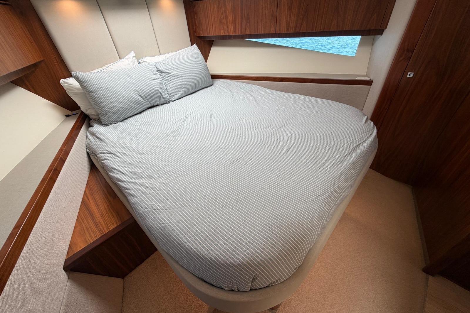Luxurious bedroom interior of 2018 Riviera 4800 Sport Yacht with elegant wood finish.