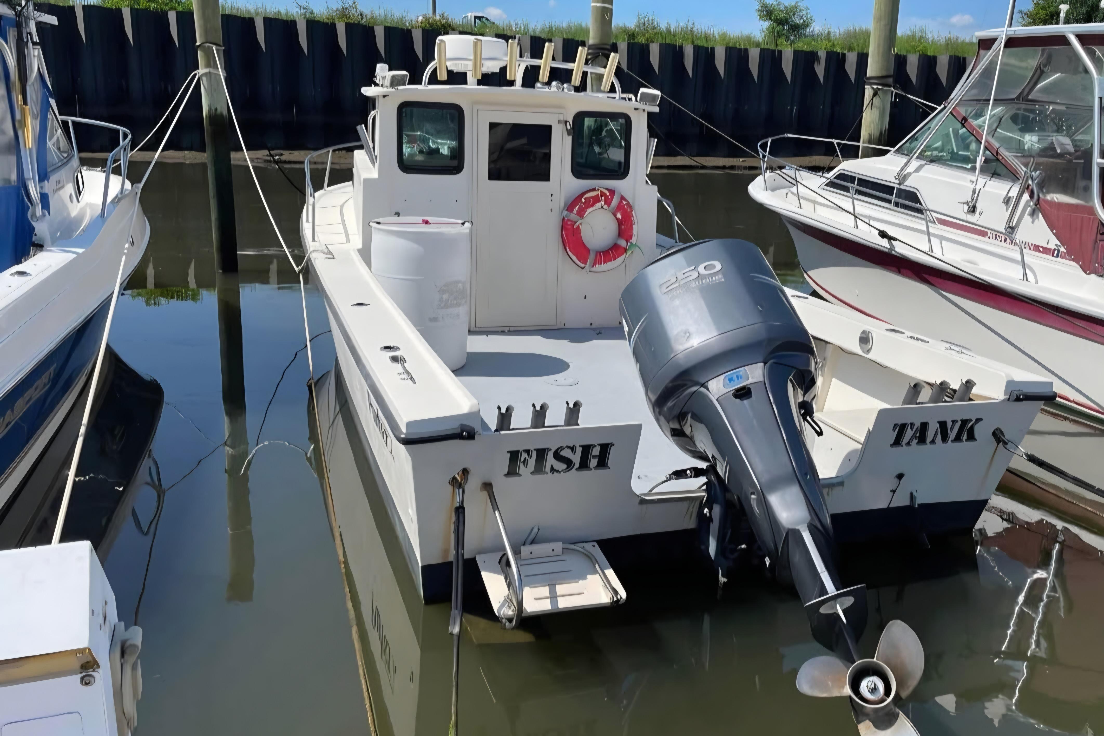 2002 Parker 2520 Deep Vee Sport Cabin boat docked with outboard motor.
