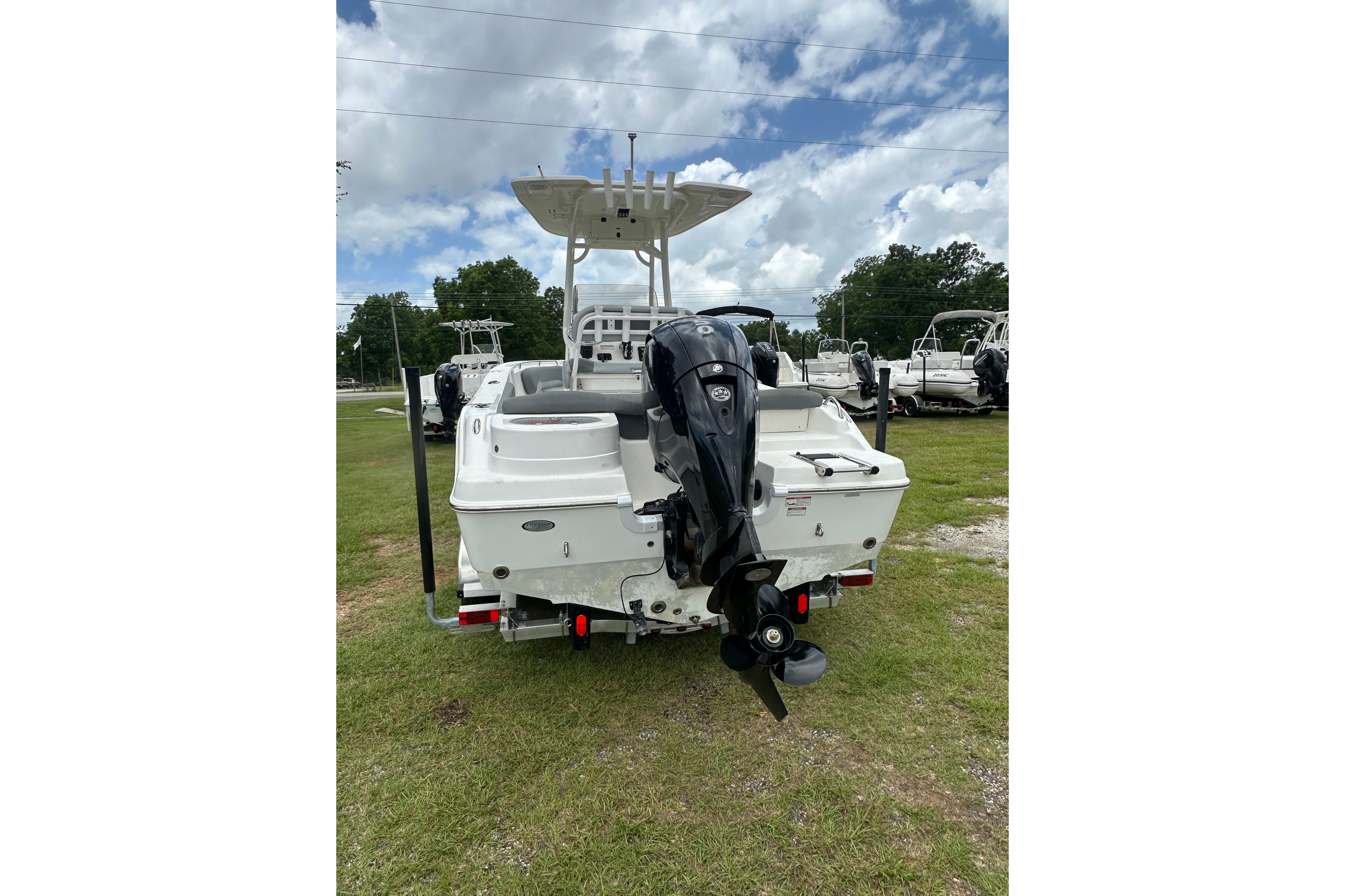 2023 NauticStar 2102 Legacy boat with outboard motor, parked on grass under cloudy sky.