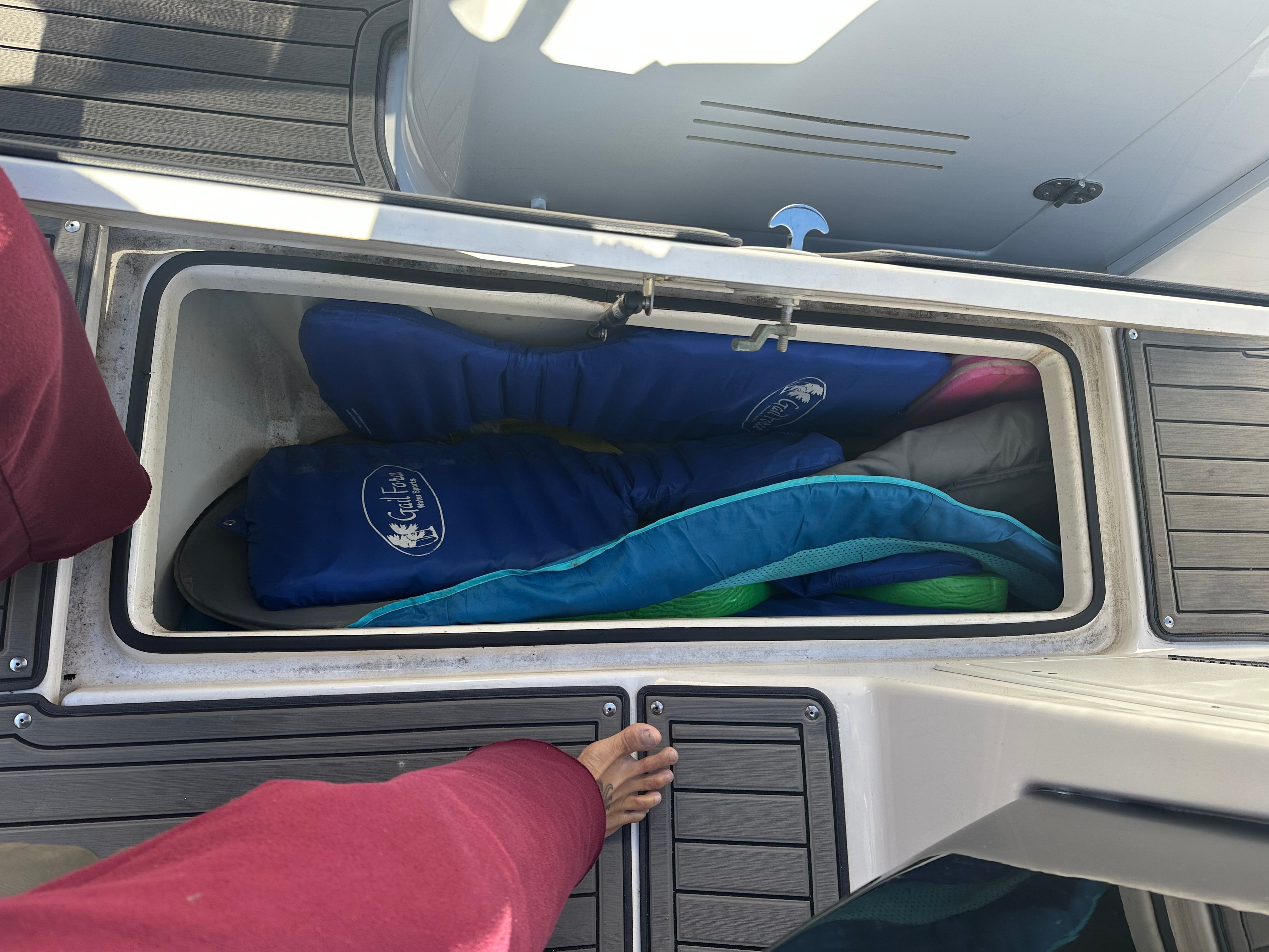 An open storage compartment on a boat with several life jackets inside.