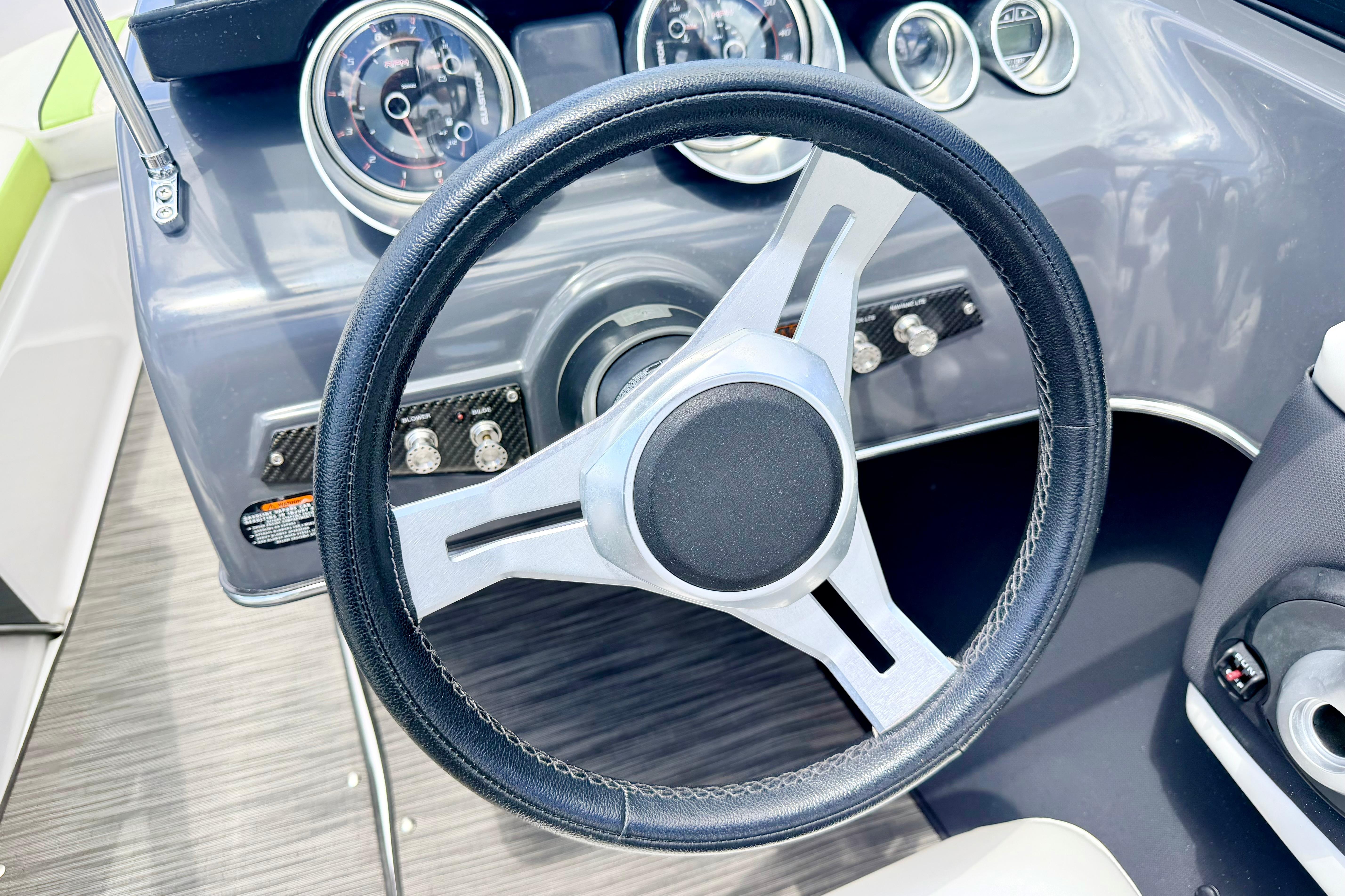 Steering wheel and dashboard of 2018 Glastron GT 185 boat, featuring modern gauges.